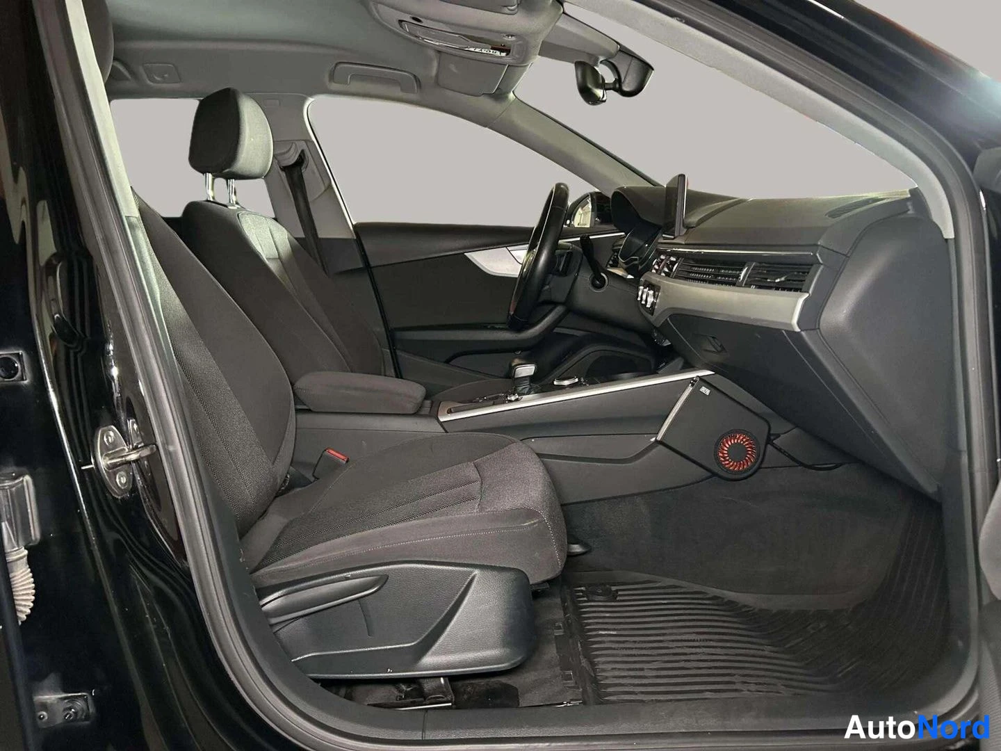 Ohjaamo: Cabin view through the open driver's side door, showing dark front seats and dashboard