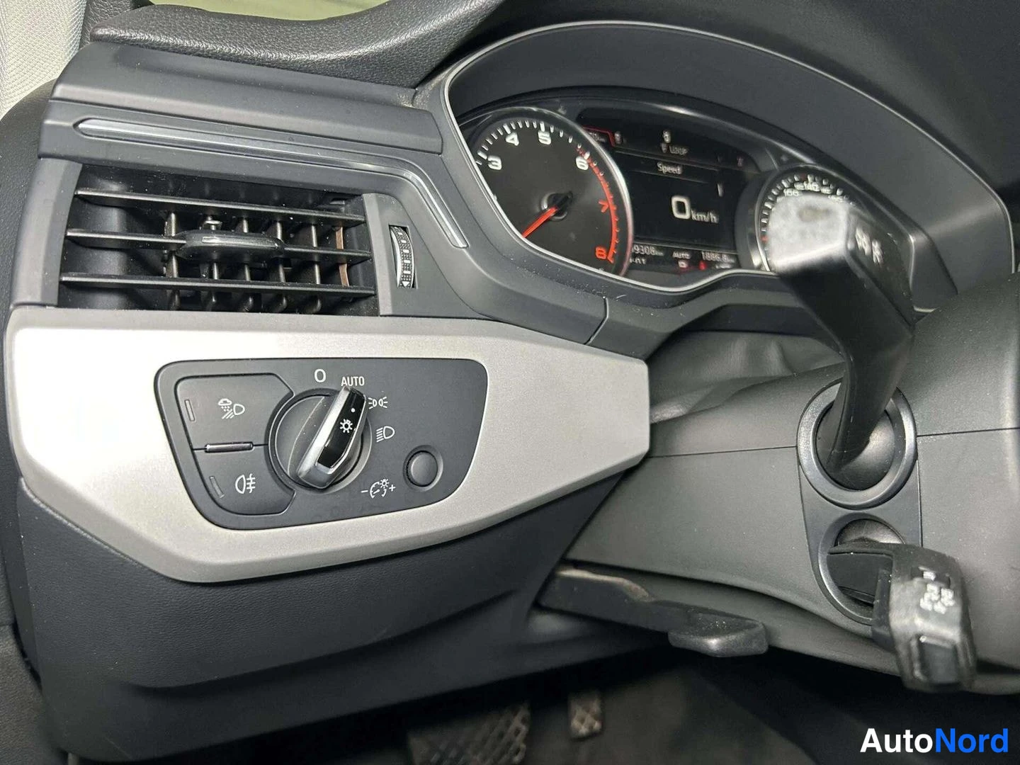 Yksityiskohta: Dashboard instrument cluster with a 'Rain Sensor' switch and light control knob to the left of the steering wheel