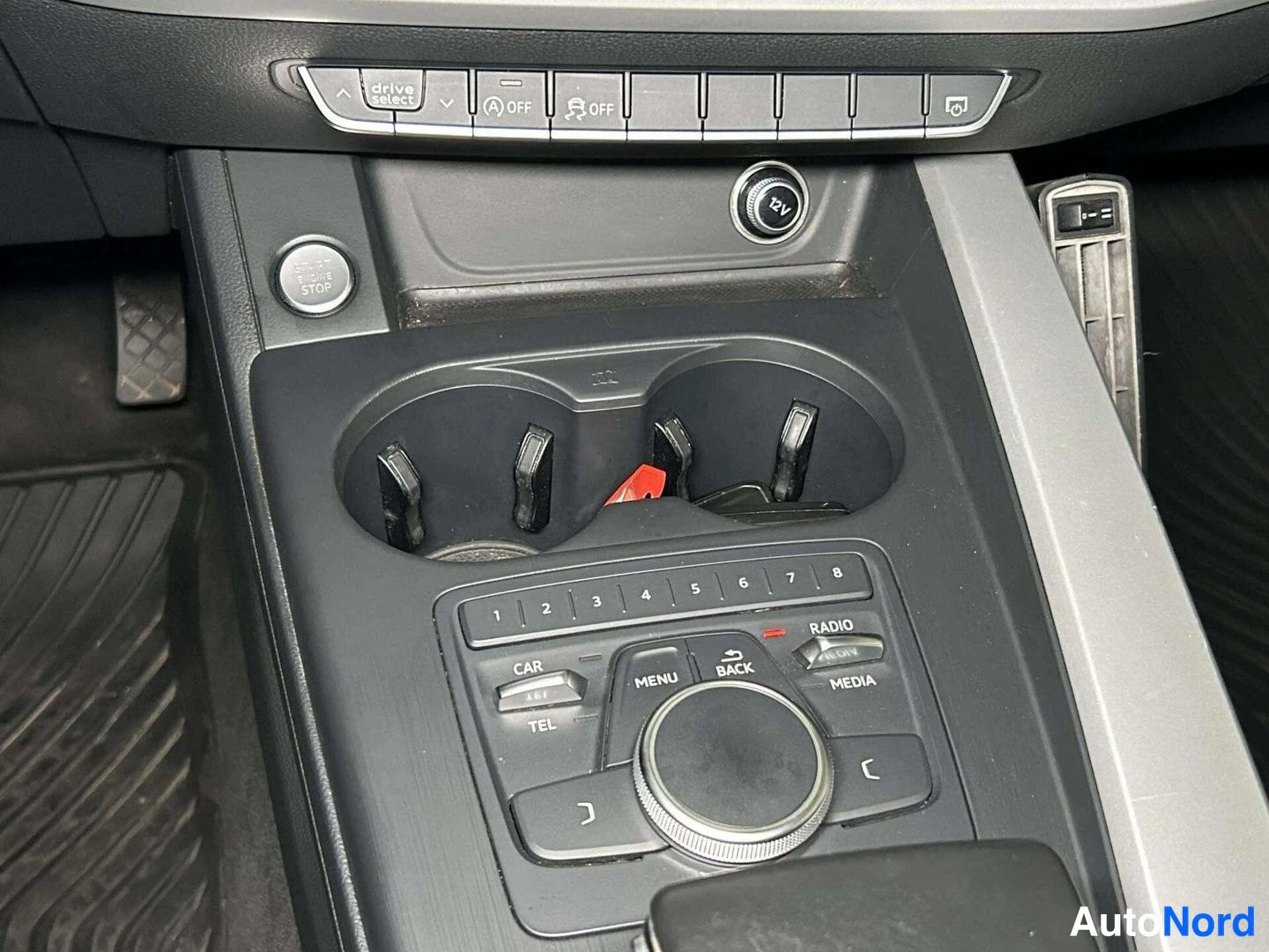 Yksityiskohta: Auton keskikonsolin yläkortti drive select- ja OFF-napeilla, 12V-pistorasia, START STOP -näppäin, kaksi kupinpidikettä ja MMI-nappipaneeli.