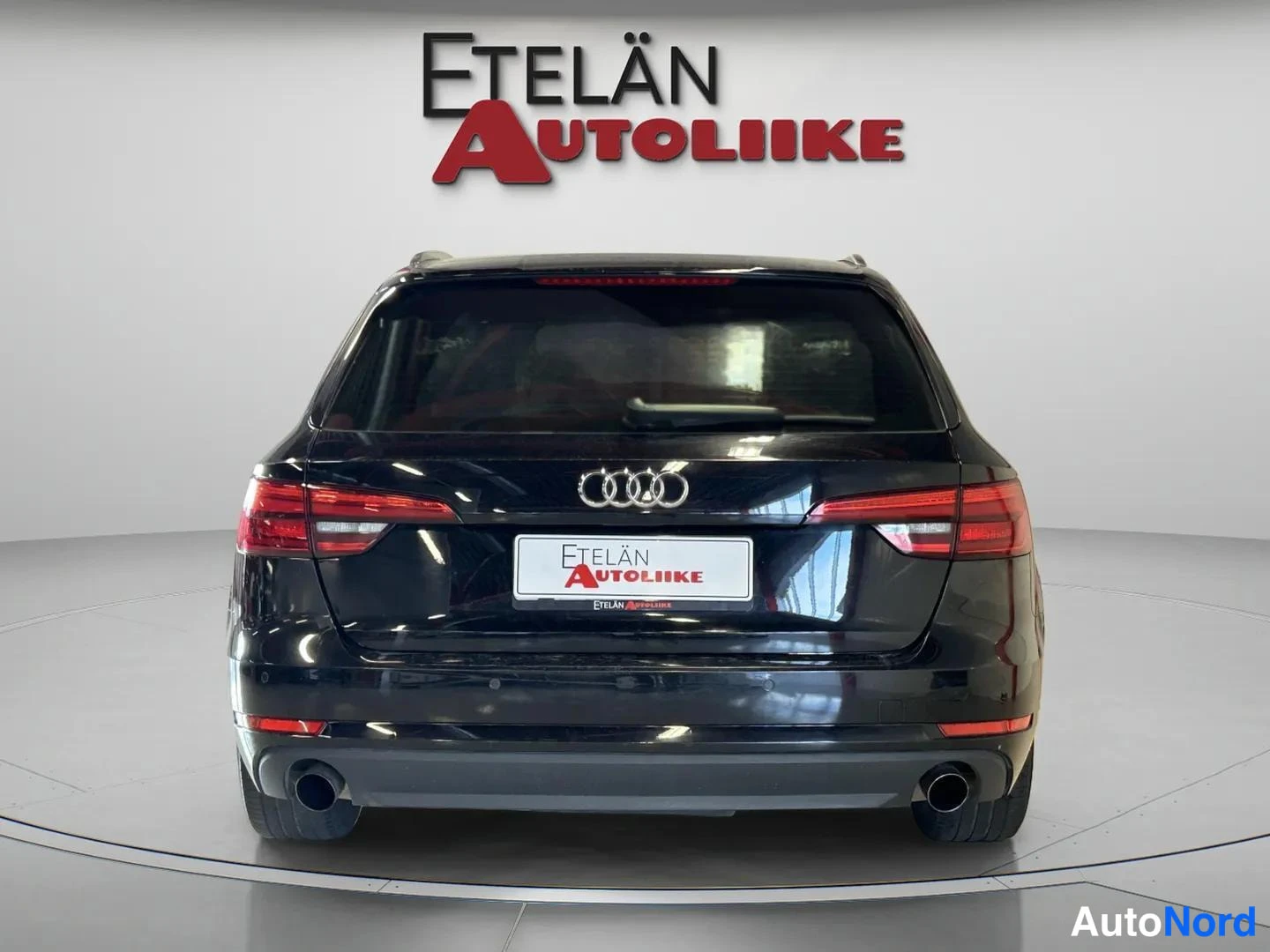 Takaa: Mustan farmariauton takaosa suoraan takaa, kaksi pakoputkea ja Audi-merkki takaluukussa.