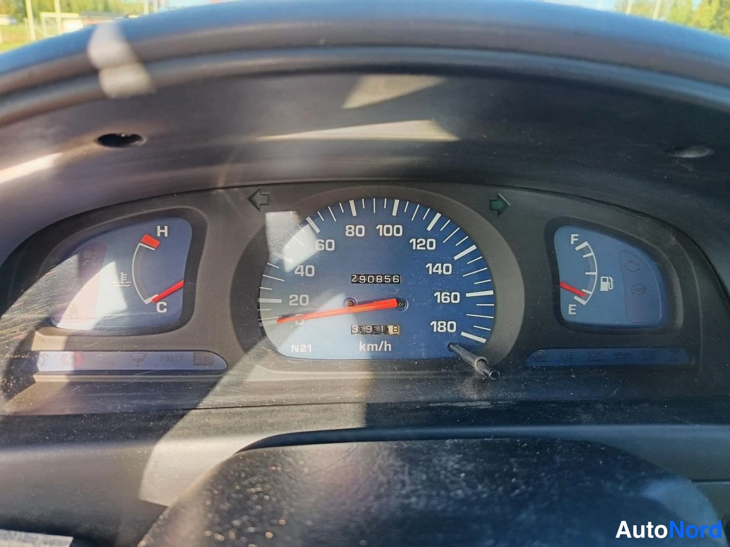 Muu: Kojelaudan mittariston lähikuva: sininen nopeusmittari 0–180 km/h, matkamittarilukema 290856, lämpömittari ja polttoainemittari.