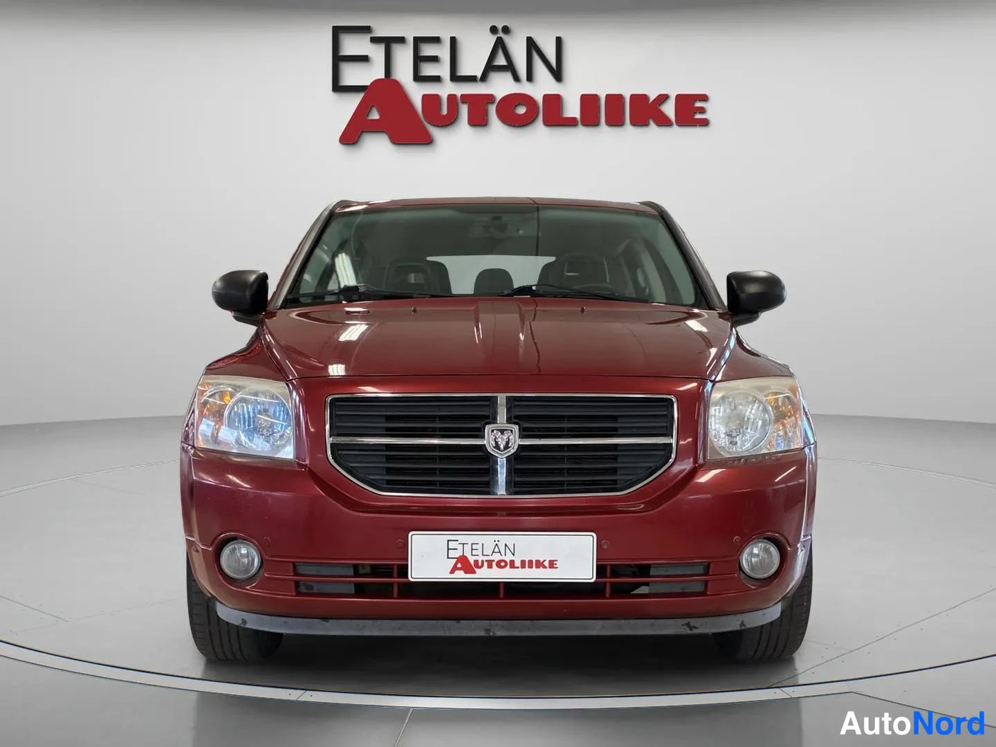 Edestä: Punainen automobiili suoraan edestä; etusäleikkö, ajovalot ja etupuskuri näkyvät.