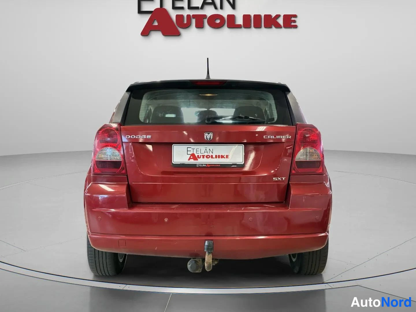 Takaa: Punaisen Dodge Caliberin suora takanäkymä: Dodge- ja Caliber-merkit, SXT-tunnus ja hinauskoukku näkyvät.
