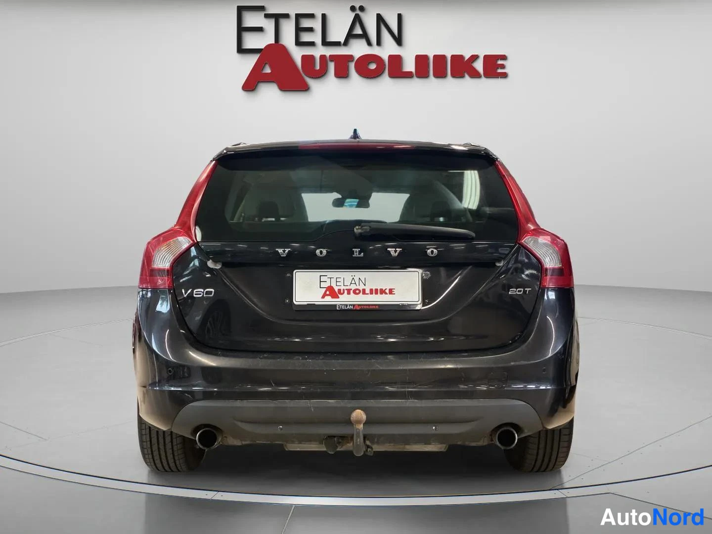Takaa: Mustan farmariauton takaosa suoraan takaa; VOLVO-, V60- ja 2.0T-tekstit, kattospoileri ja kaksi pakoputkea näkyvät.