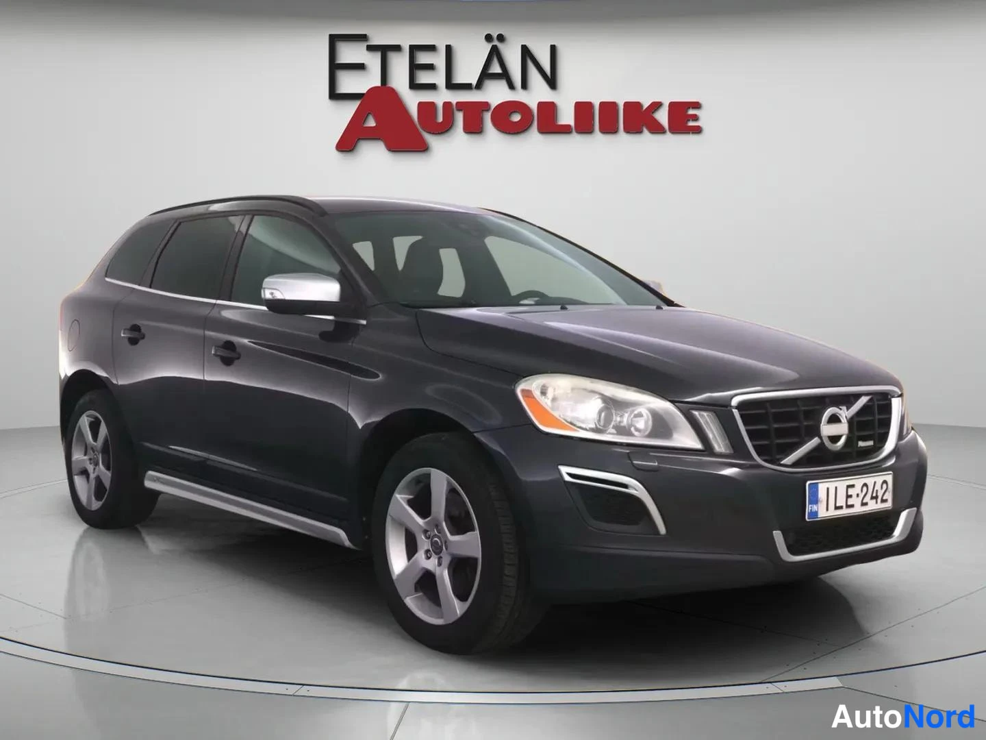 Etuviisto, nokka oikealle: Harmaa Volvo XC60 -maasturin etkoliskokuva rekisterikilvellä '', hieman epäterävissä otoksessa studiovalaistuksessa.