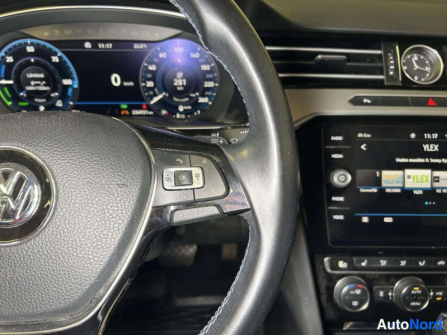 Muu: Sisätilakuva Volkswagenin ohjauspyörästä ja digitaalisesta mittaristosta, näytössä nopeus 0 km/h, matkamittari 232921 km sekä keskikäyttöjärjestelmä YLE-kanavil