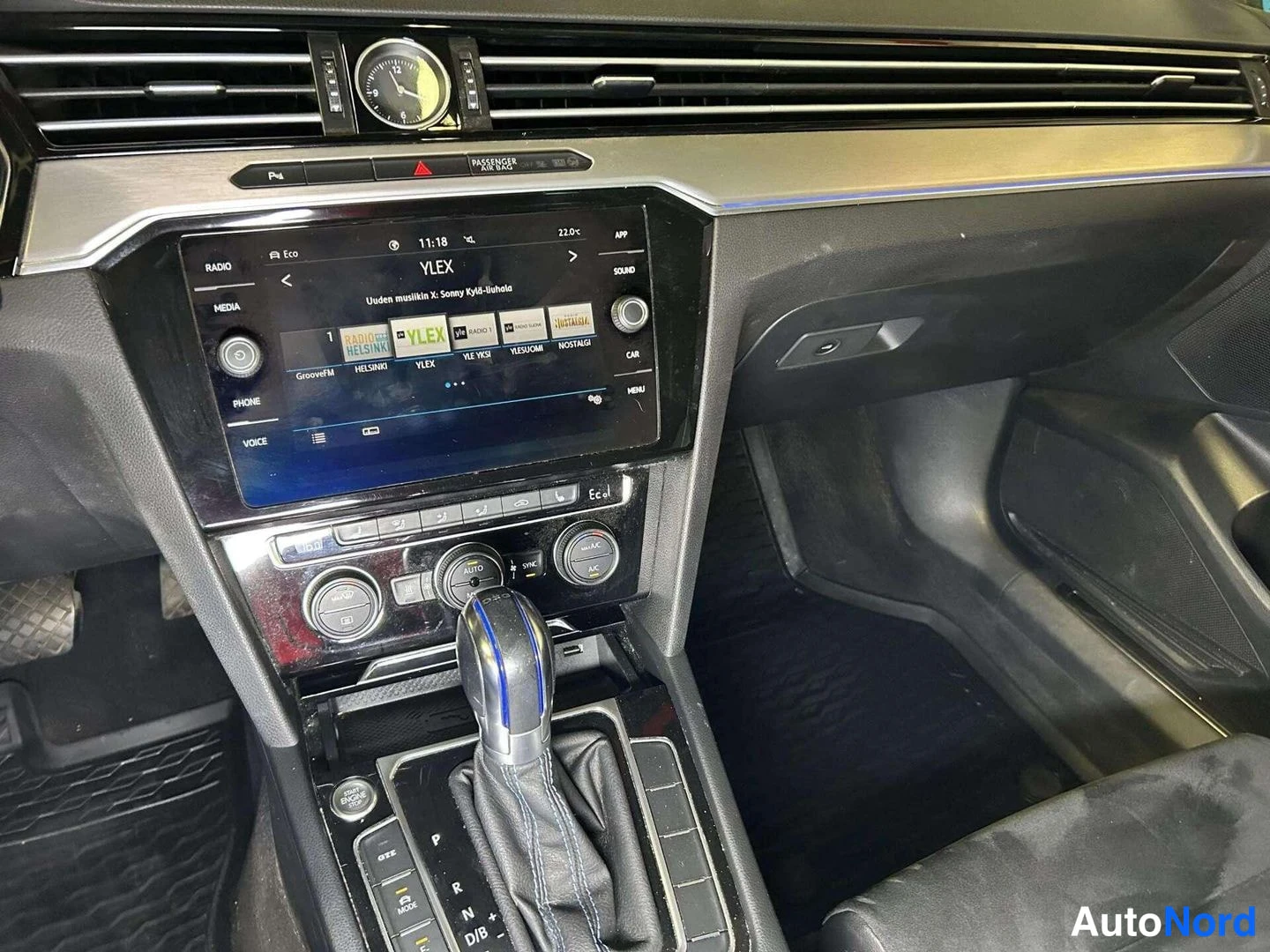 Muu: Volkswagenin keskikonsoli: kosketusnäyttö radioasemineen, automaattivaihteen valitsin, kaksivyöhykeilmastoinnin napit ja analoginen kello kojelaudassa.