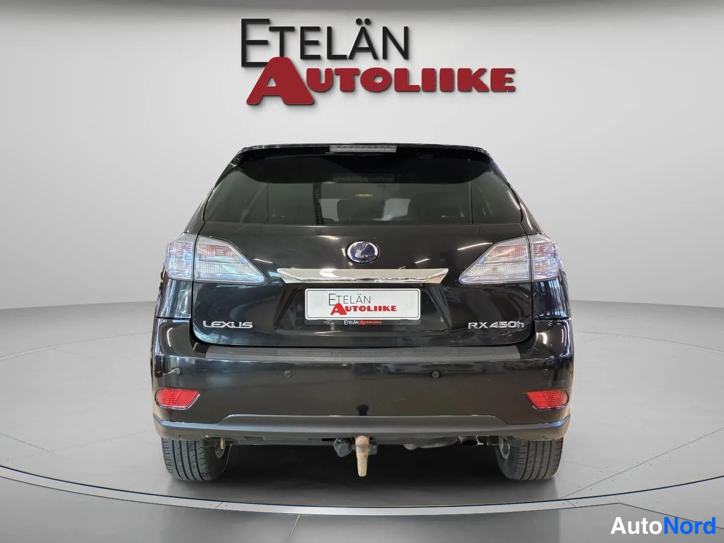 Takaa: Lexus RX:n takaosa suoraan takaa;LEXUS- ja RX 450h -tekstit, takavalot ja perävaunukoukku näkyvät mustassa korissa.