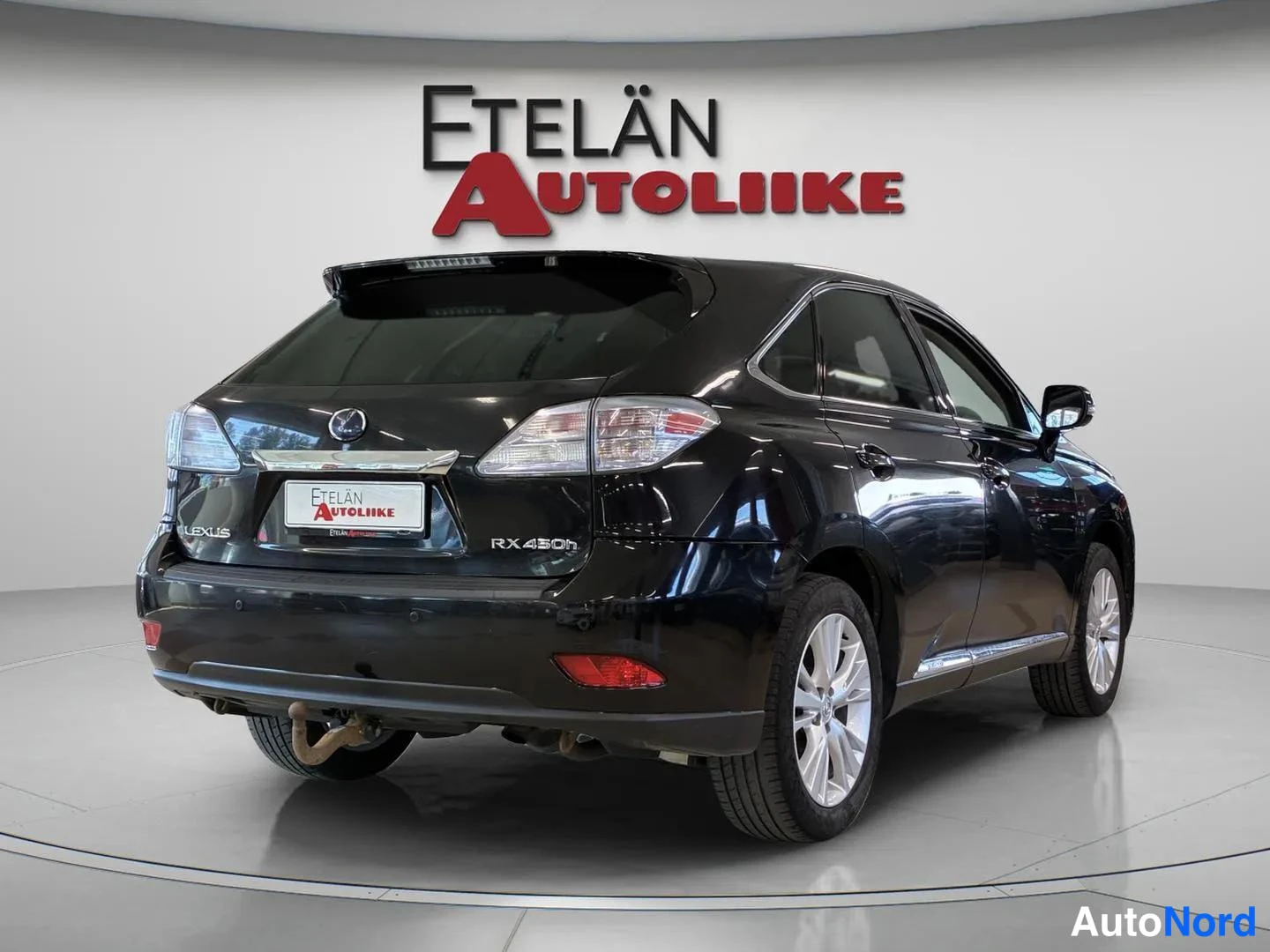 Takaviisto: Lexus RX:n takakulma oikealta; musta kori, RX 450h -merkintä, kromilistat ja hopeavanteet näkyvät.