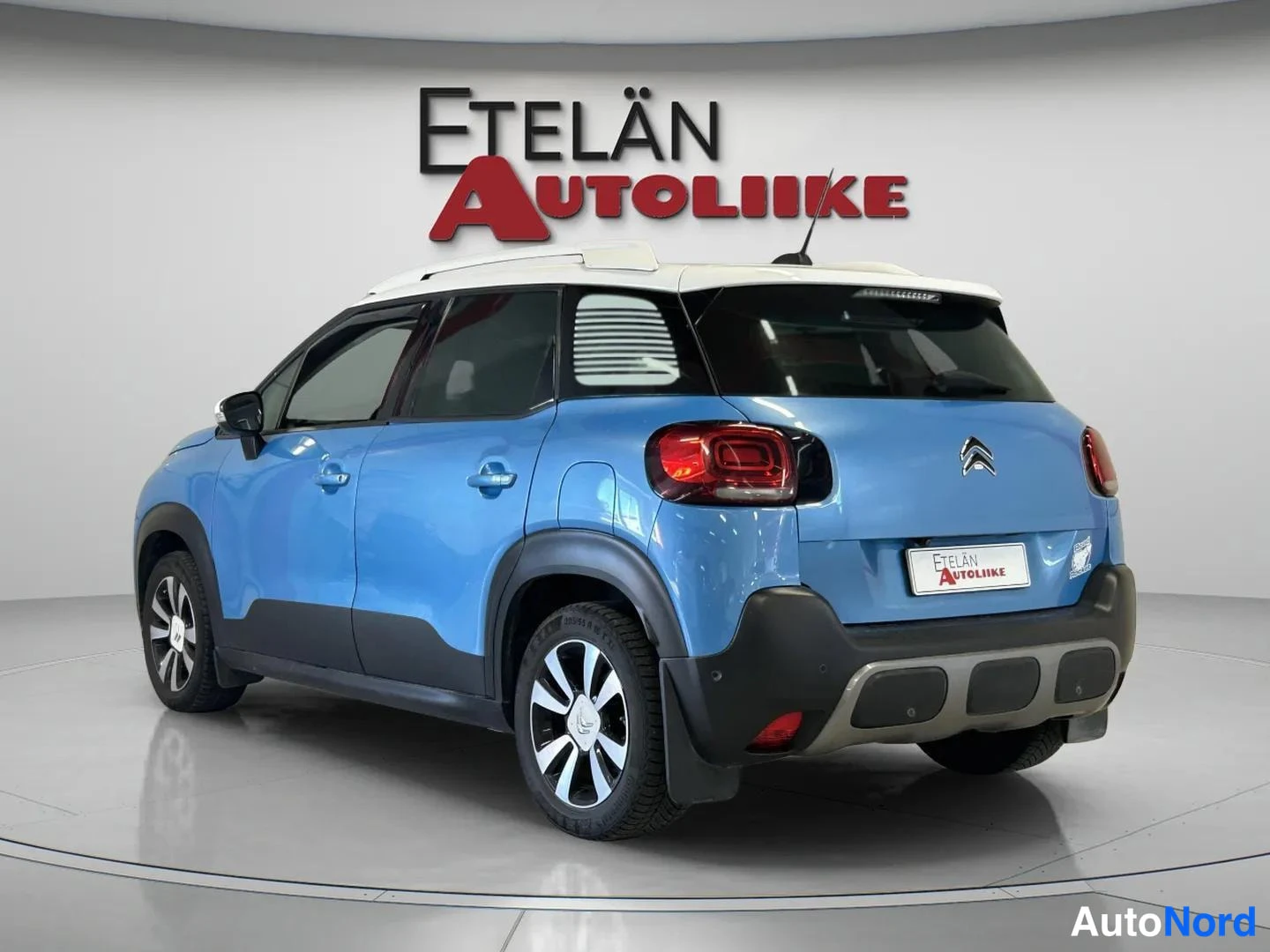 Takaviisto: Sinisen Citroenin takakulma vasemmalta, valkoinen katto ja Etelän Autoliike -merkki taustalla.