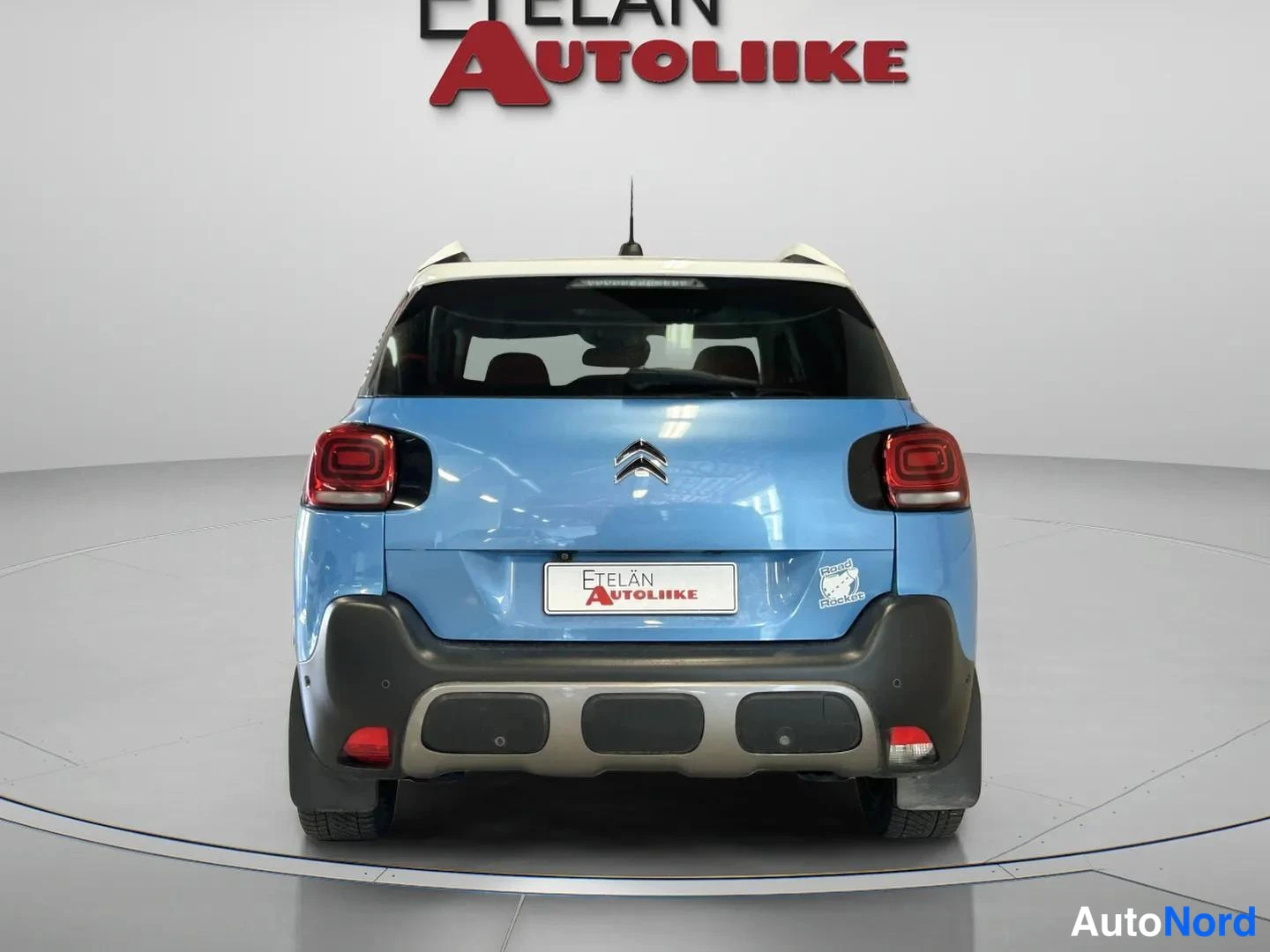 Takaa: Sinisen Citroenin takanäkymä suoraan takaa, valkoinen katto ja Etelän Autoliike -kyltti takaluukussa.