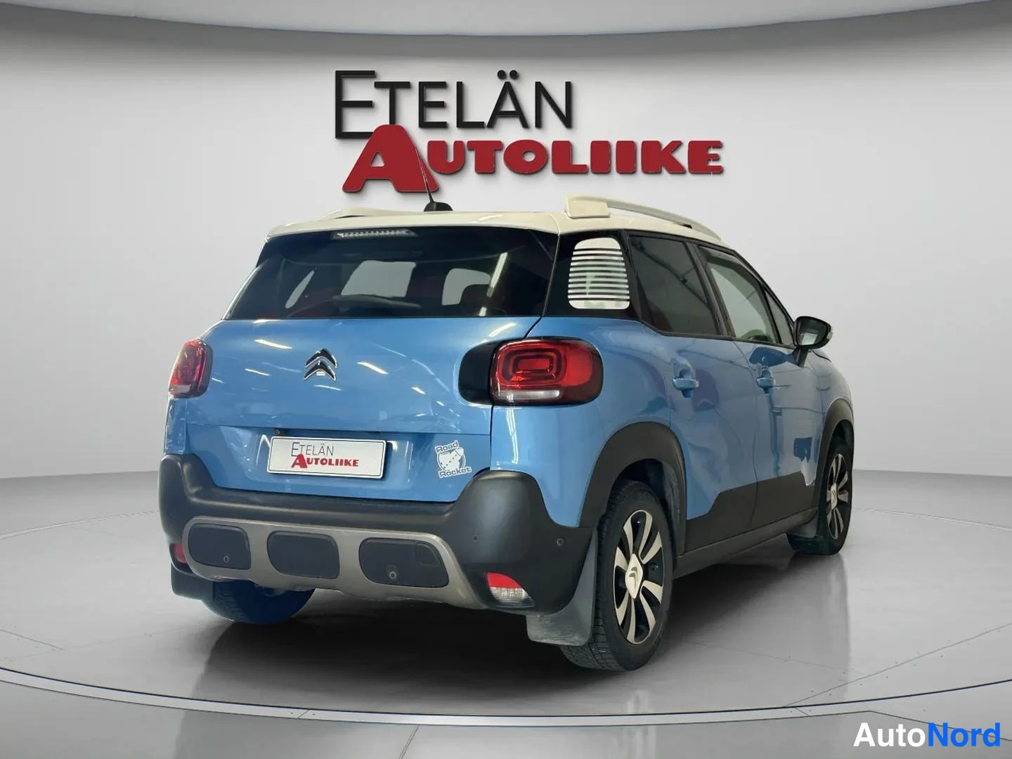 Takaviisto: Sinisen Citroenin takakulma oikealta, valkoinen katto ja Etelän Autoliike -merkki taustalla.