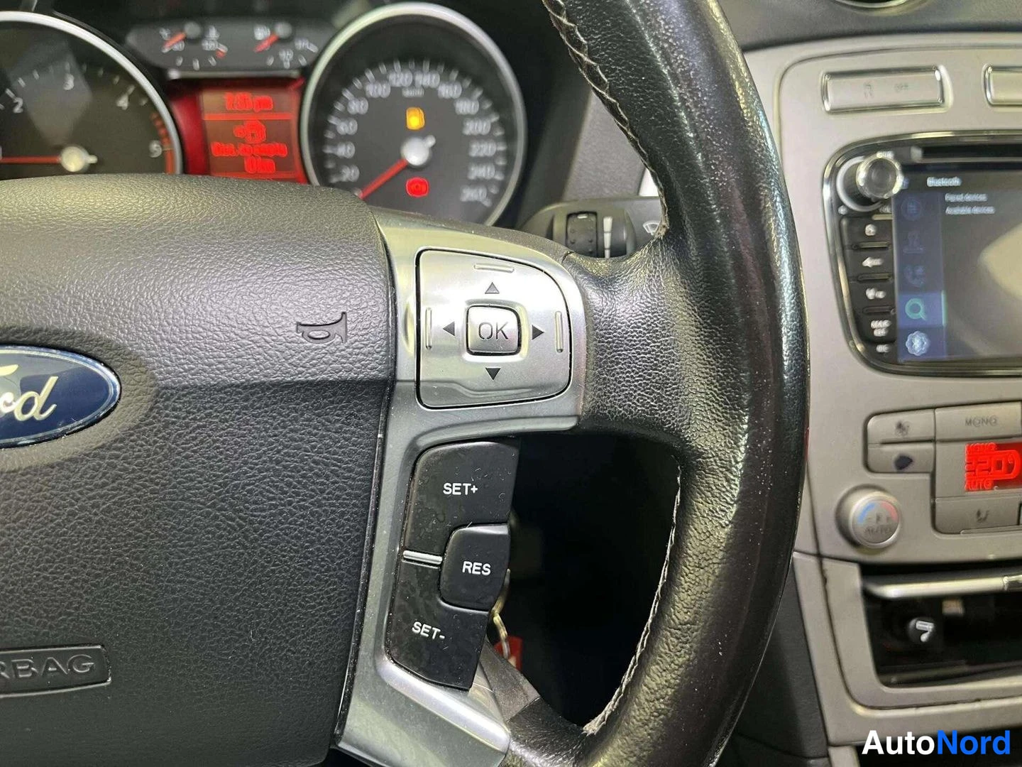 Muu: Ohjauspyörän cruise control -painikkeet ja infotainment-näyttö lähikuvassa.