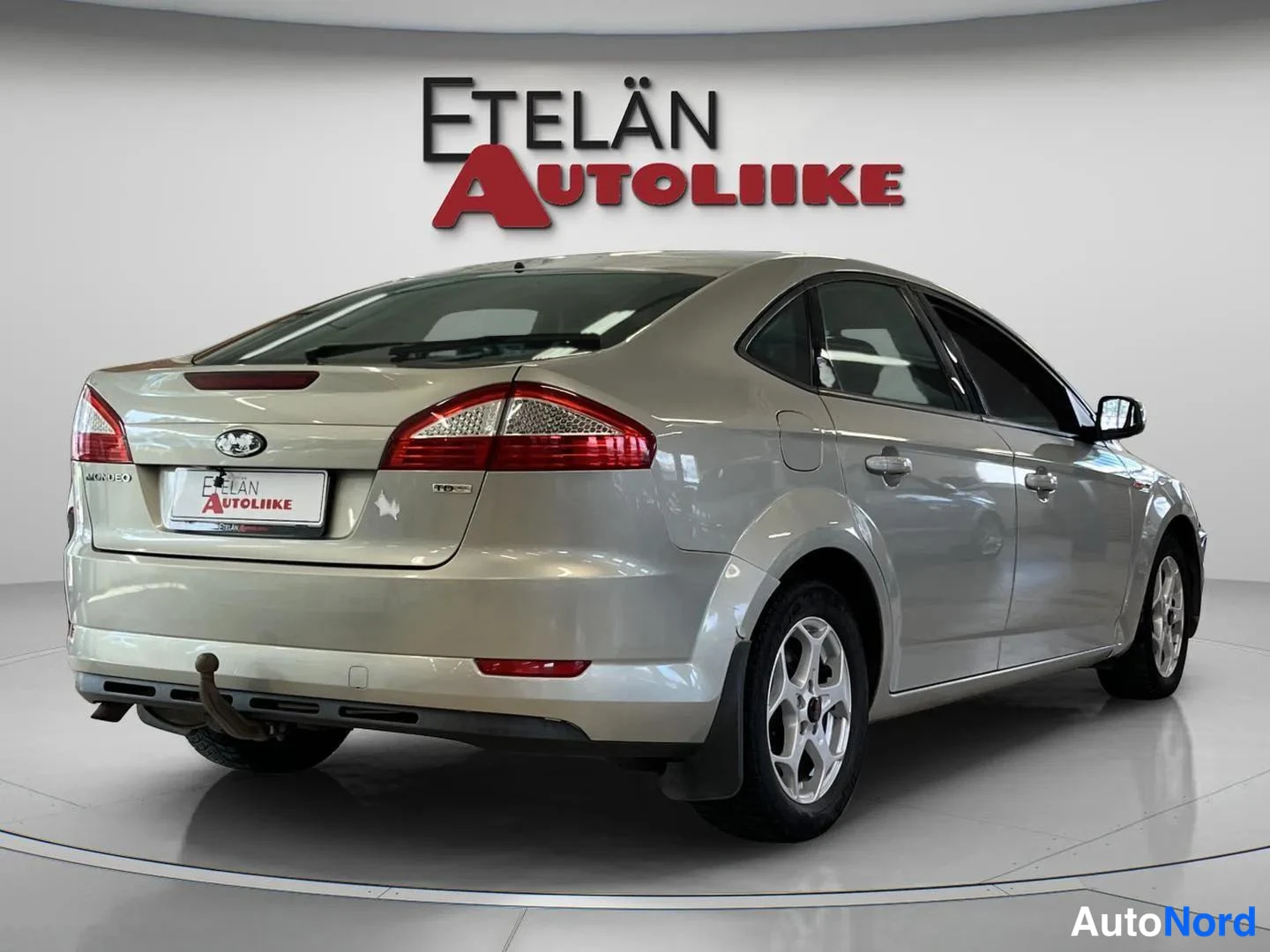 Takaviisto: Auton takaosa ja oikea kylki vinosta takaa; beige Ford Mondeo, kyljen ovien ja pyörien näkyvissä.