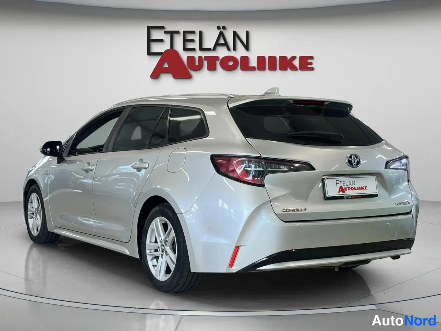 Takaviisto: Hopeanvärinen Toyota Corolla -farmari takaa sivusta kuvattuna näyttämöllä, Etelän Autoliike-tunnus taustalla.
