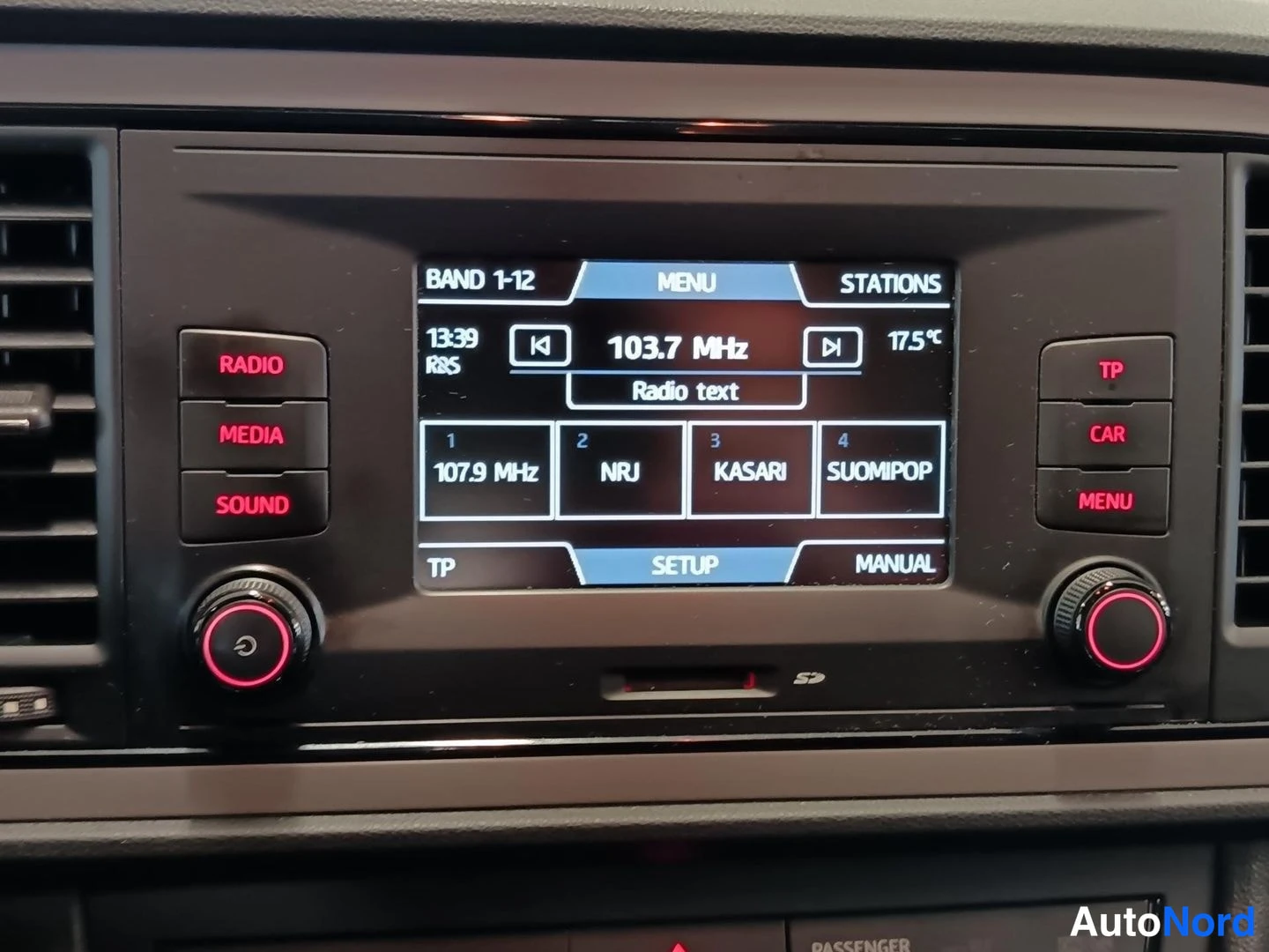 Yksityiskohta: Auton radioviritin näyttää taajuuden 103,7 MHz, kanavina NRJ, KASARI ja SUOMIPOP.