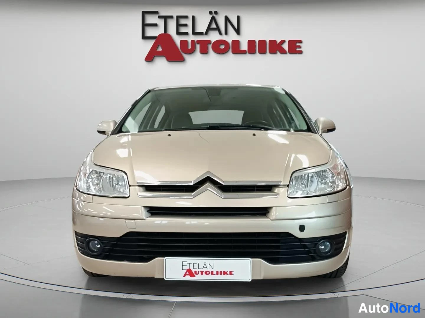 Edestä: Beige Citroën C4 henkilöauto suoraan edestä studiotaustaa vasten.