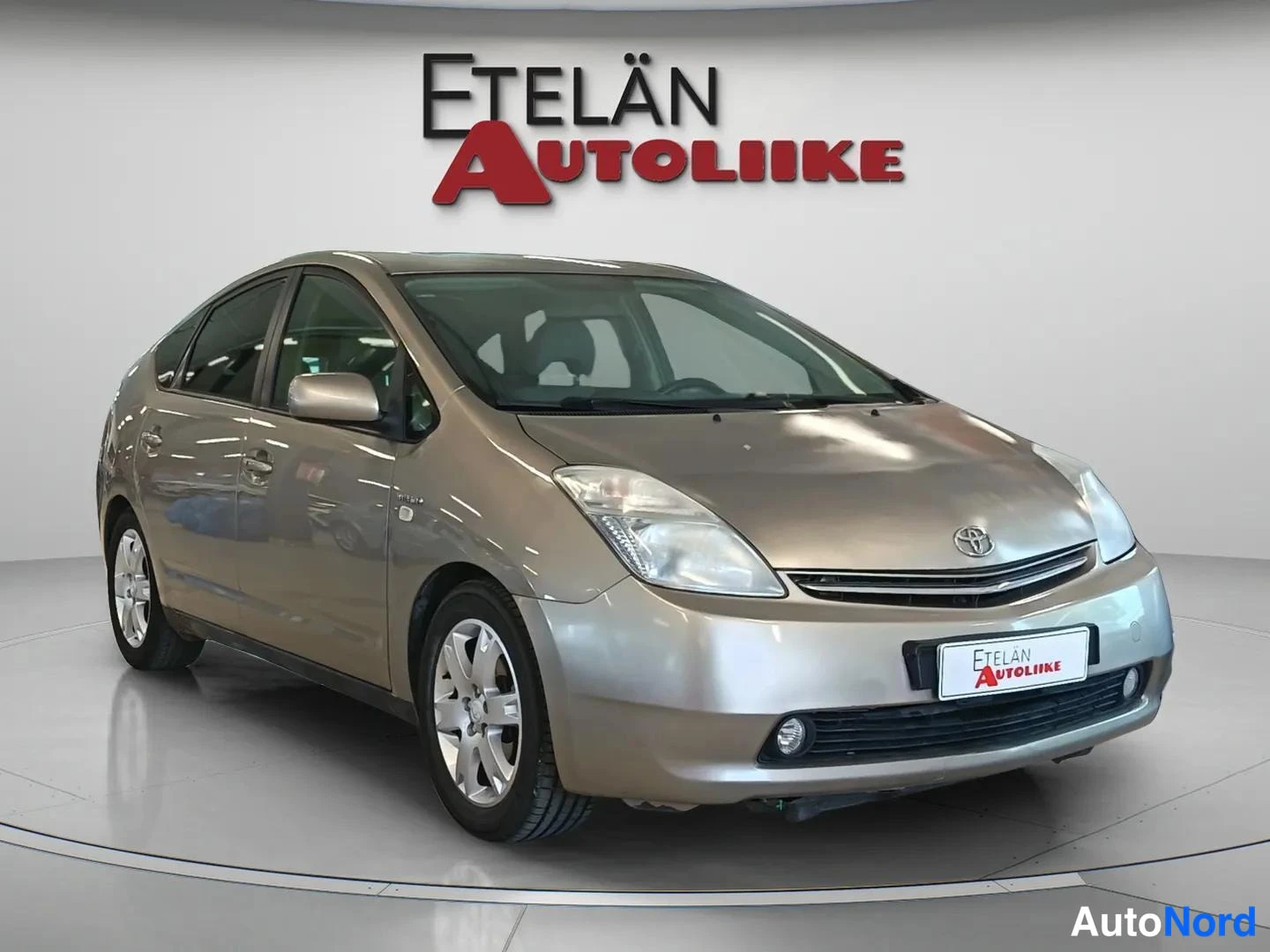 Etuviisto, nokka oikealle: Toyota Prius 2008, etukulmakuva, nokka oikealla; vaaleanprunensävyinen kori, katvekuva studiotyyppisessä valaistuksessa.