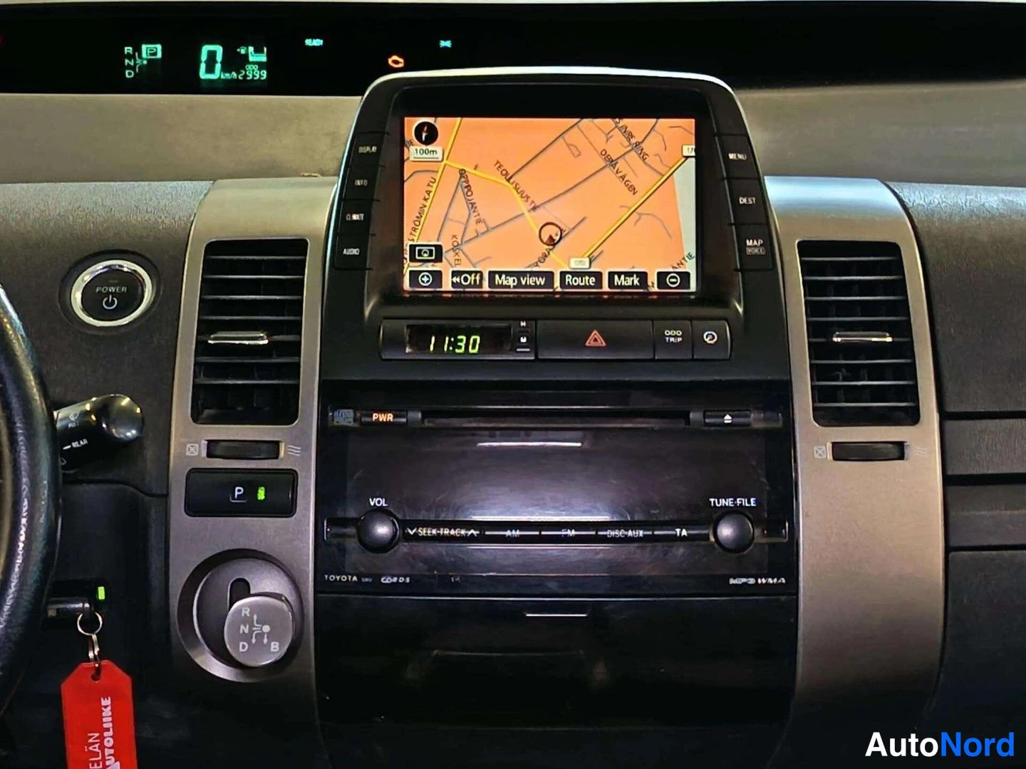 Muu: Kojelaudan infotainment-näyttö näyttää karttaa, keskikonsolissa radio ja ilmastointiautomaatin säätimet.