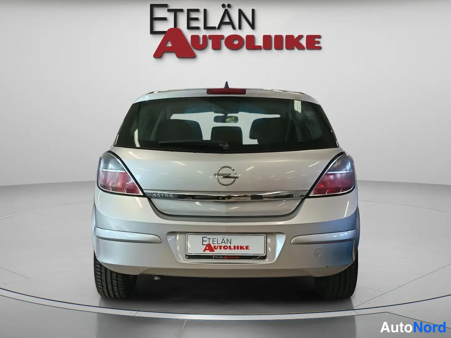 Takaa: Hopeanvärinen Opel Astra -henkilöauto suoraan takaa kuvattuna, takaluukussa Opel-merkki ja ASTRA-teksti, rekisterikilven paikalla Etelän Autoliike -mainoslaatta