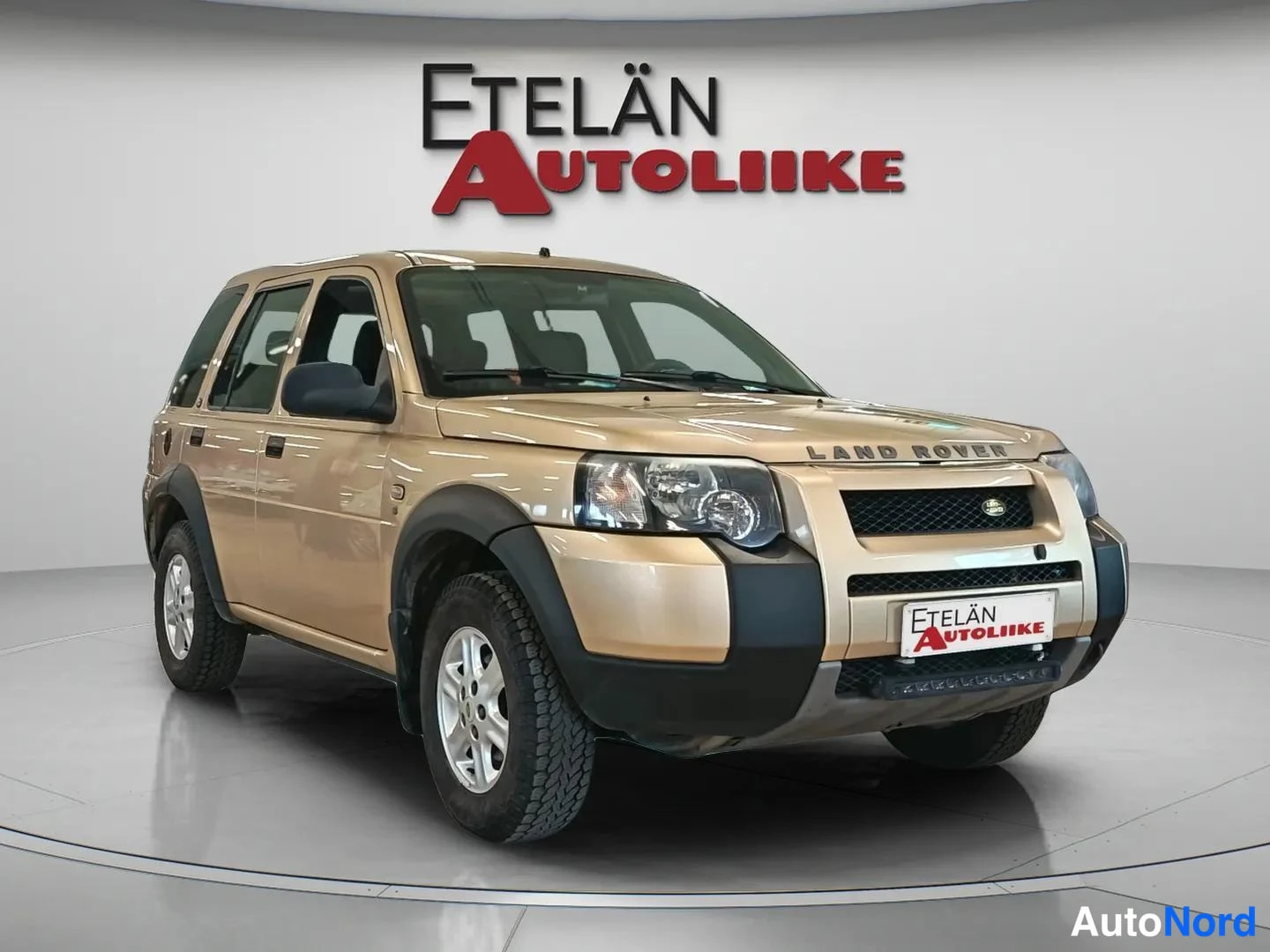 Etuviisto, nokka oikealle: Beige Land Rover Freelander -kylki-etunurkka studiossa, Etelän Autoliike-tausta.