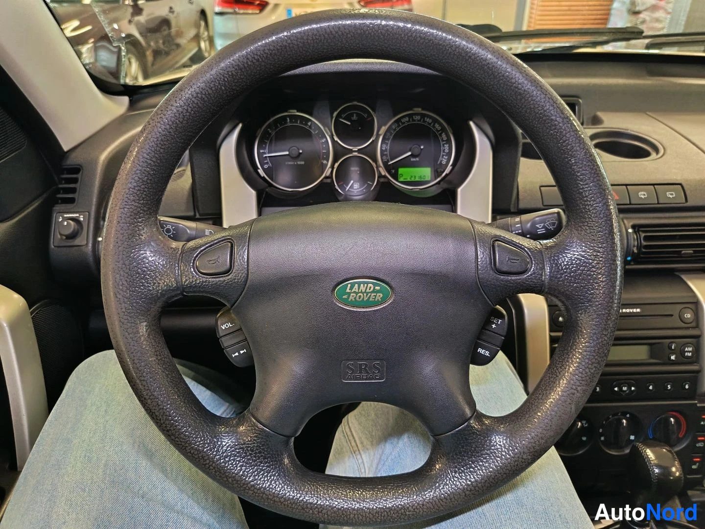 Muu: Ohjauspyörä edestä: Land Rover -merkki, SRS-ajovaloteksti, äänenvoimakkuus- ja vakionopeudensäätönäppäimillä, taustalla nelinumeroiset mittarit.