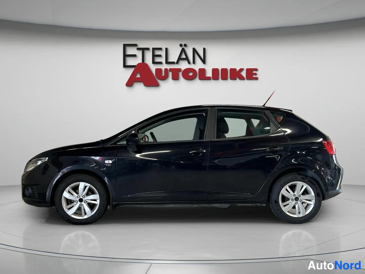 Sivulta: Mustan viisiovisen tila-auton sivukuva studiossa, Etelän Autoliikkeen logo taustalla.