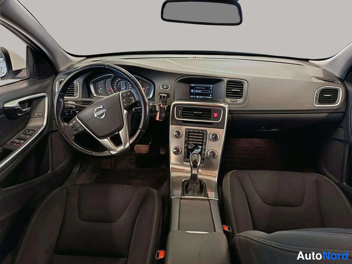 Muu: Volvo V60:n etusija ohjaamosta: musta ohjauspyörä, mittaristo, keskikonsolin näyttö ja automaattivaihteen valitsin sekä kaksi tummaa etuistuinta.