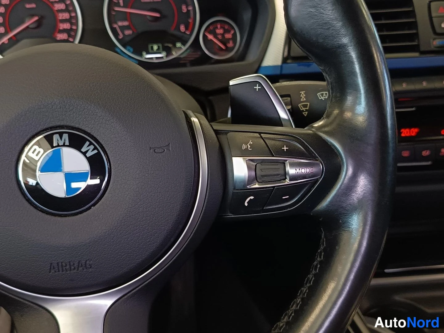 Yksityiskohta: BMW-logollisen ruorin oikea puoli, napit MODE ja puhelin, vaihdevipu +
