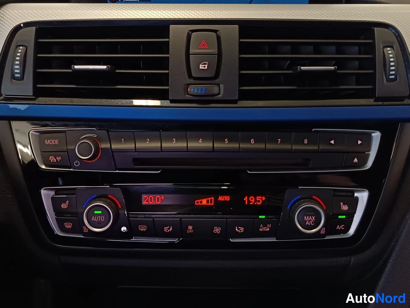 Edestä: Auton kojelaudan keskiosa: automaattinen ilmastointipaneeli (AUTO 20,0° ja 19,5°, MAX A/C) sekä radio-MODE-säädin.