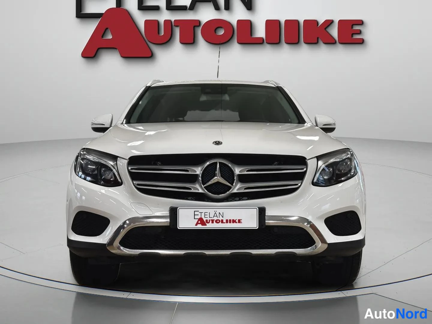 Edestä: Valkoisen Mercedes-Benz GLC:n suora etunäkymä, etusäleikkö ja Mercedes-tähti näkyvissä.