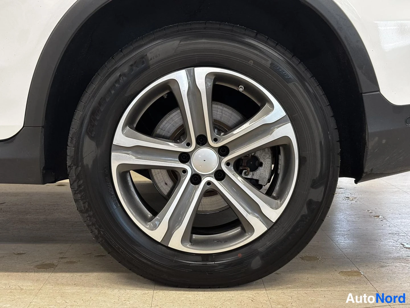 Muu: Lähikuva auton pyörästä: tumma viisipolviseksi alumiinivanne ja Bridgestone-rengas.