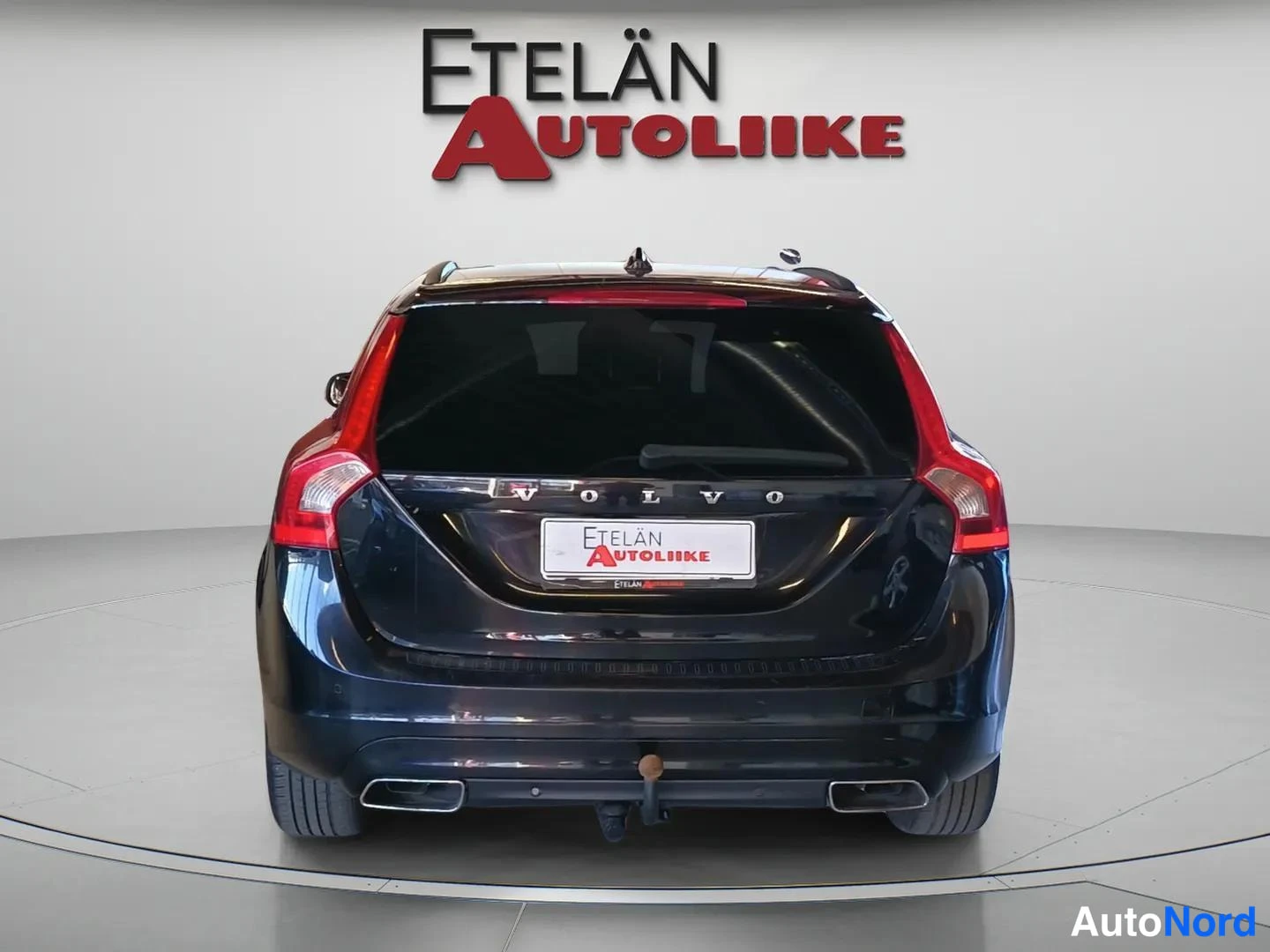 Takaa: Auton takaosan suorakuva: musta farmari, VOLVO-teksti ja vetokoukku, taustalla Etelän Autoliike -logo.