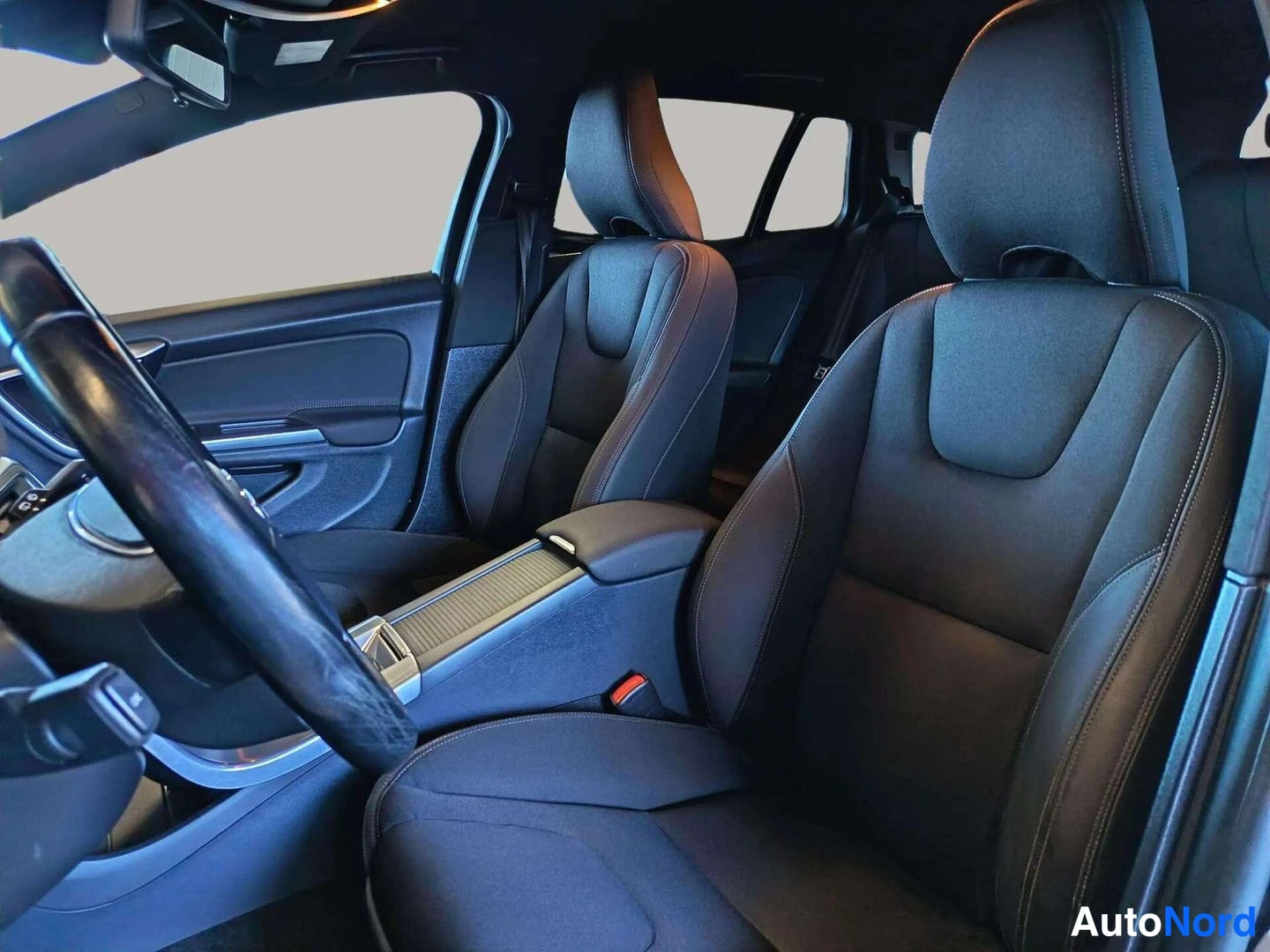 Etuviisto, nokka vasemmalle: Volvo V60 front seats and centre armrest photographed through the open driver's door