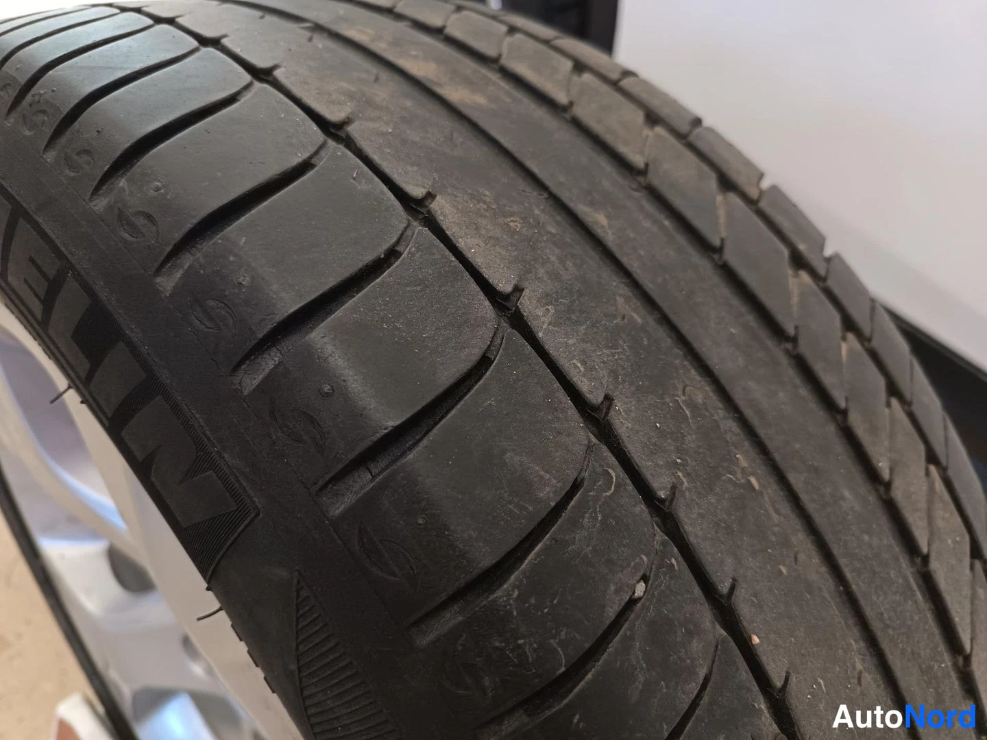 Yksityiskohta: Lähikuva Michelin-kesärengkaan kulutuspinnasta hopeanvärisen vanneen päällä.