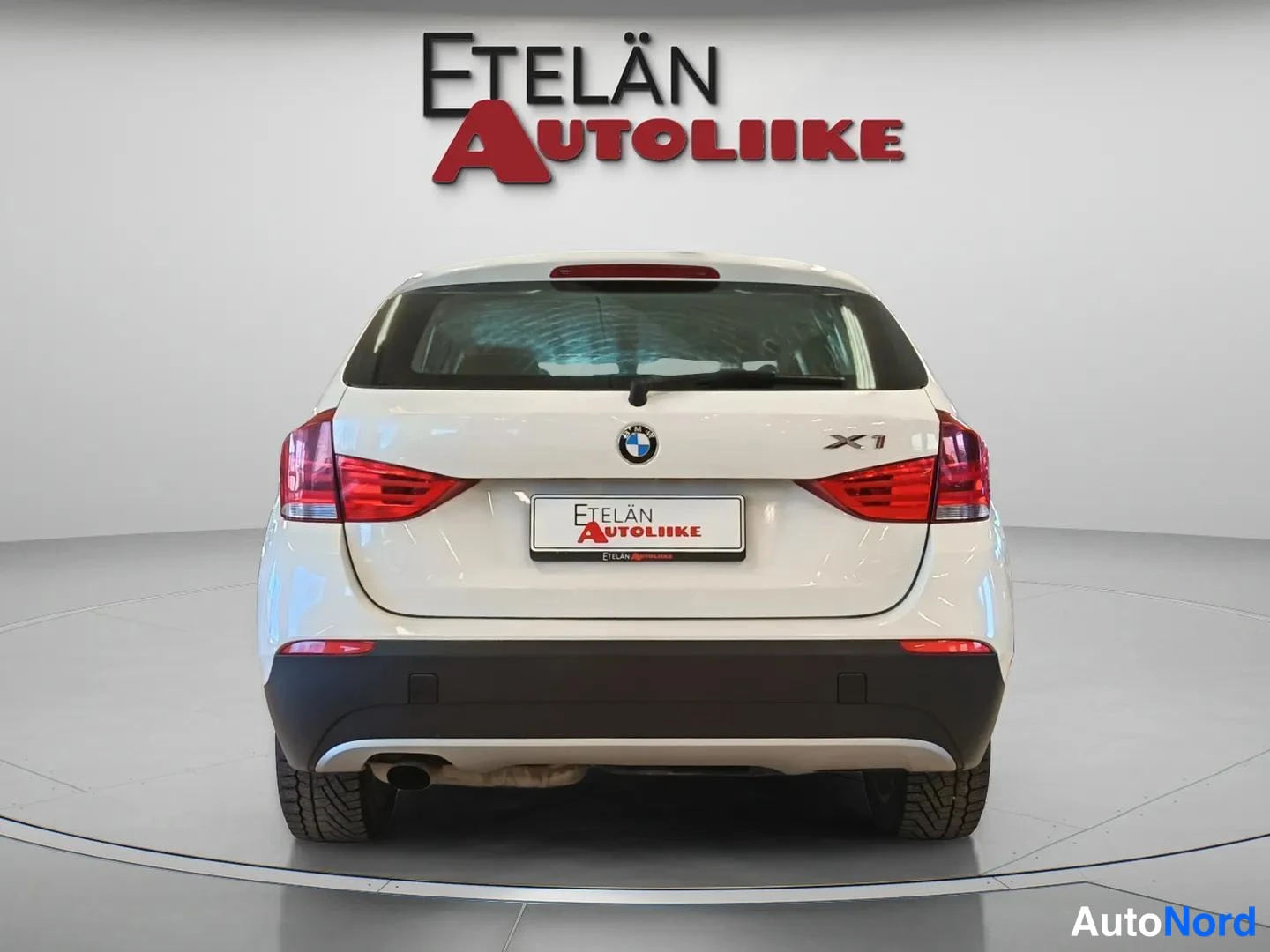 Takaa: Valkoinen BMW X1 suoraan takaa kuvattuna, Etelän Autoliike -kyltti rekisterikilven paikalla.