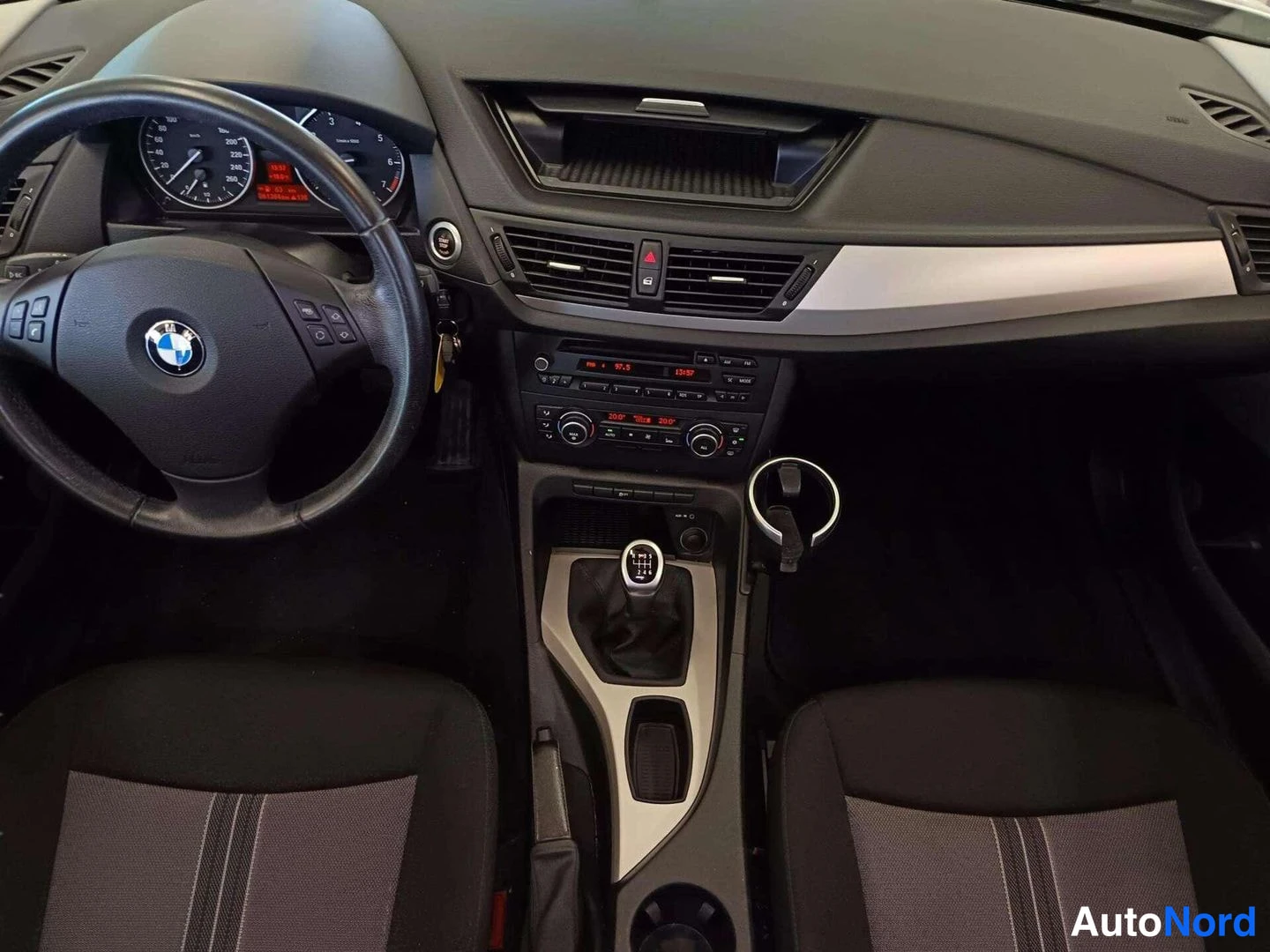 Muu: Kojelauta ja keskitunneli ylhäältä: BMW-ohjauspyörä, manuaalivaihteen kahva, viinilasi ja radio