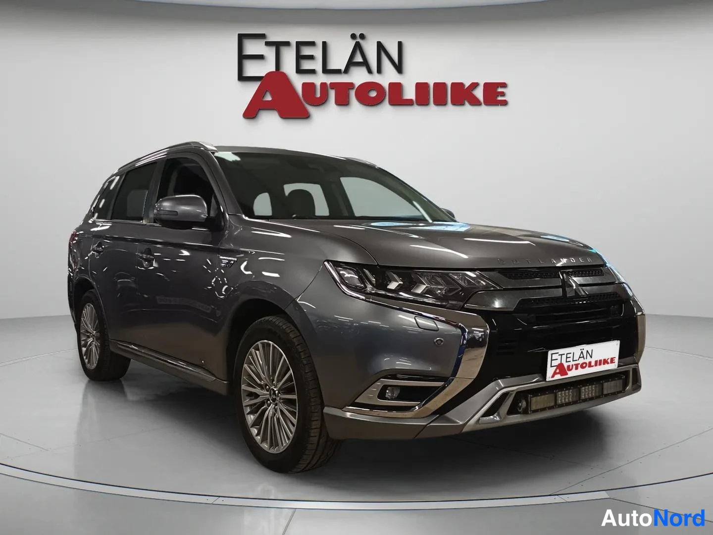 Etuviisto, nokka oikealle: Auton etukulma oikealta, maalitoharmaa crossover-tyyppinen auto studiovaloisassa tilassa, Etelän Autoliike -kyltti etupuskurissa.