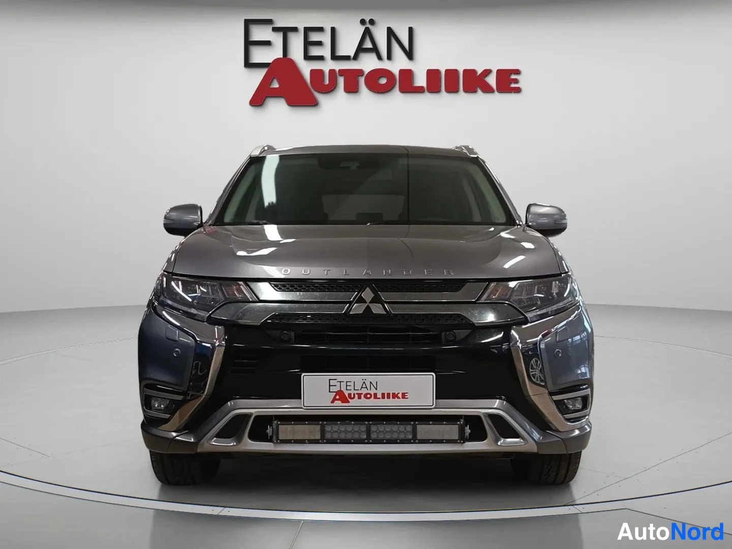 Edestä: Auto suoraan edestä päin, maski ja ajovalot näkyvät, Etelän Autoliike -kyltti etupuskurissa.