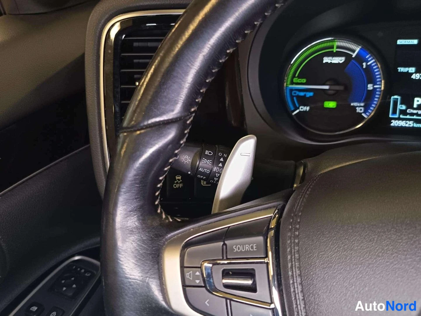 Muu: Ohjauspyörän vasen puoli ja mittaristo, jossa näkyy OUTLANDER PHEV -hybriditehomittari (Eco/Charge), matkamittari 209625 km ja SOURCE-nappi.