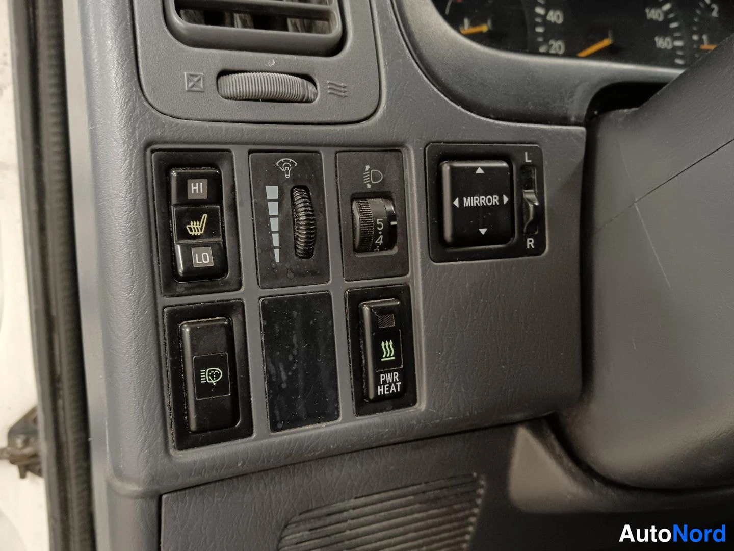 Ohjaamo: Interior cabin close-up showing a control panel with buttons for heated front seats (labeled HI and LO), mirror adjustment controls, light intensity adjustment