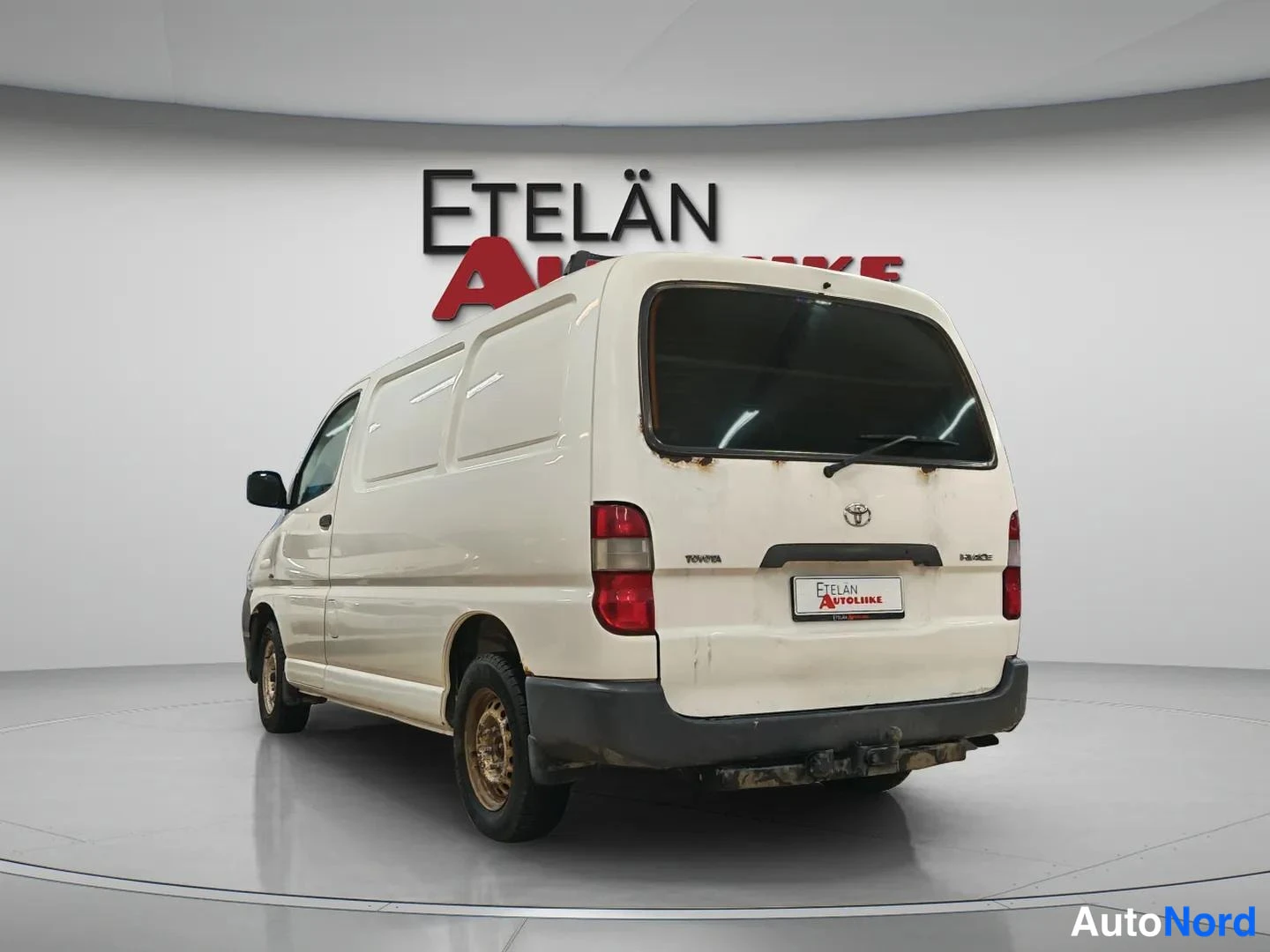 Takaviisto: Toyota Hiace -pakettiauto takaa viistosti valkoisena studiovalaistuksessa.