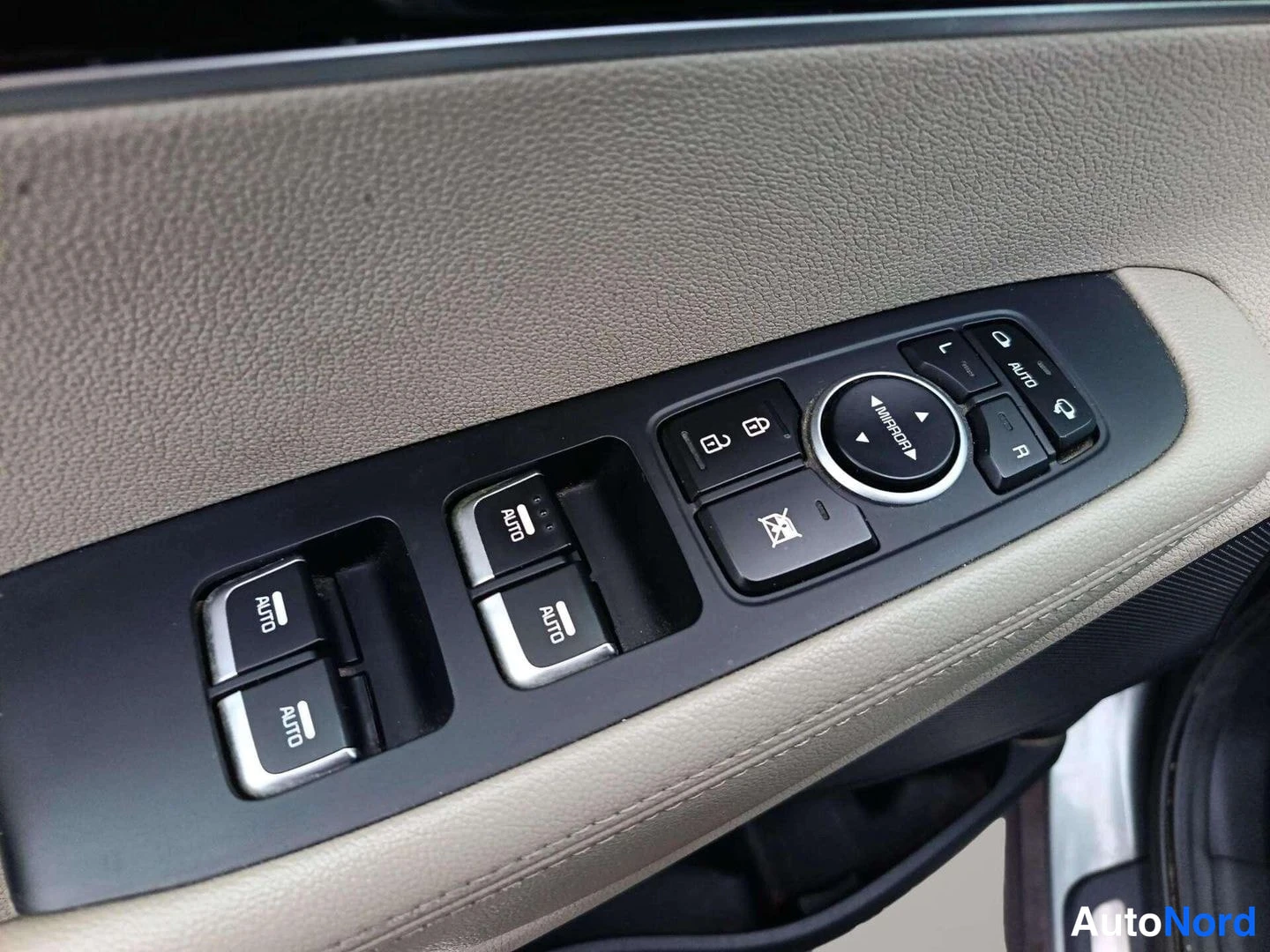 Yksityiskohta: Driver-side door control panel with four power window switches featuring 'AUTO' labels and a rotary mirror selector