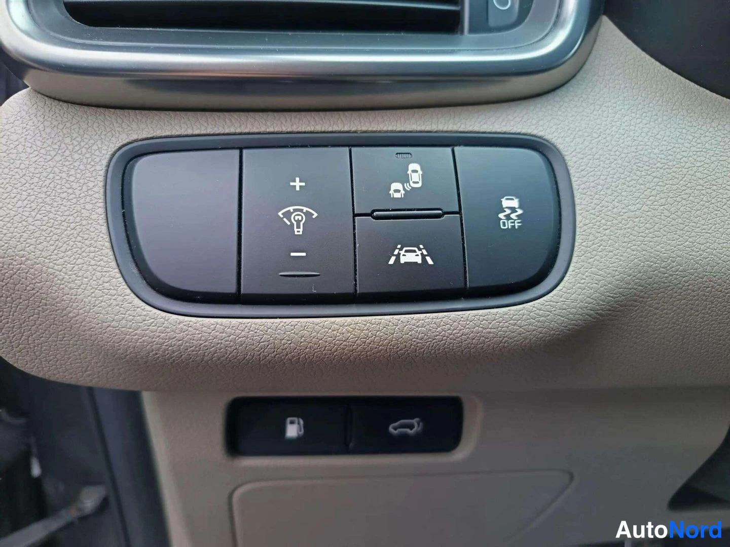 Yksityiskohta: Dashboard control cluster showing LED brightness adjustment (+/-), lane departure warning (lanes icon), parking sensor (radar car icon) and ESP off button