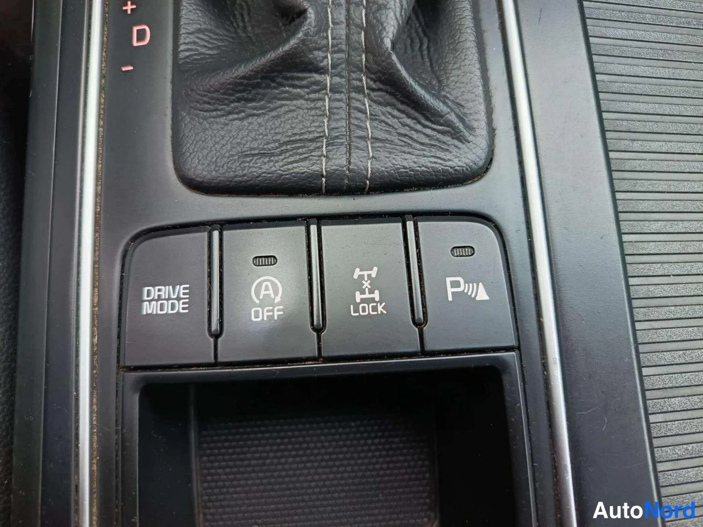 Yksityiskohta: Center console buttons including DRIVE MODE selection, A OFF (auto start-stop switch), X LOCK (4-wheel drive lock) and PARK SENSOR switch next to gear lever boo