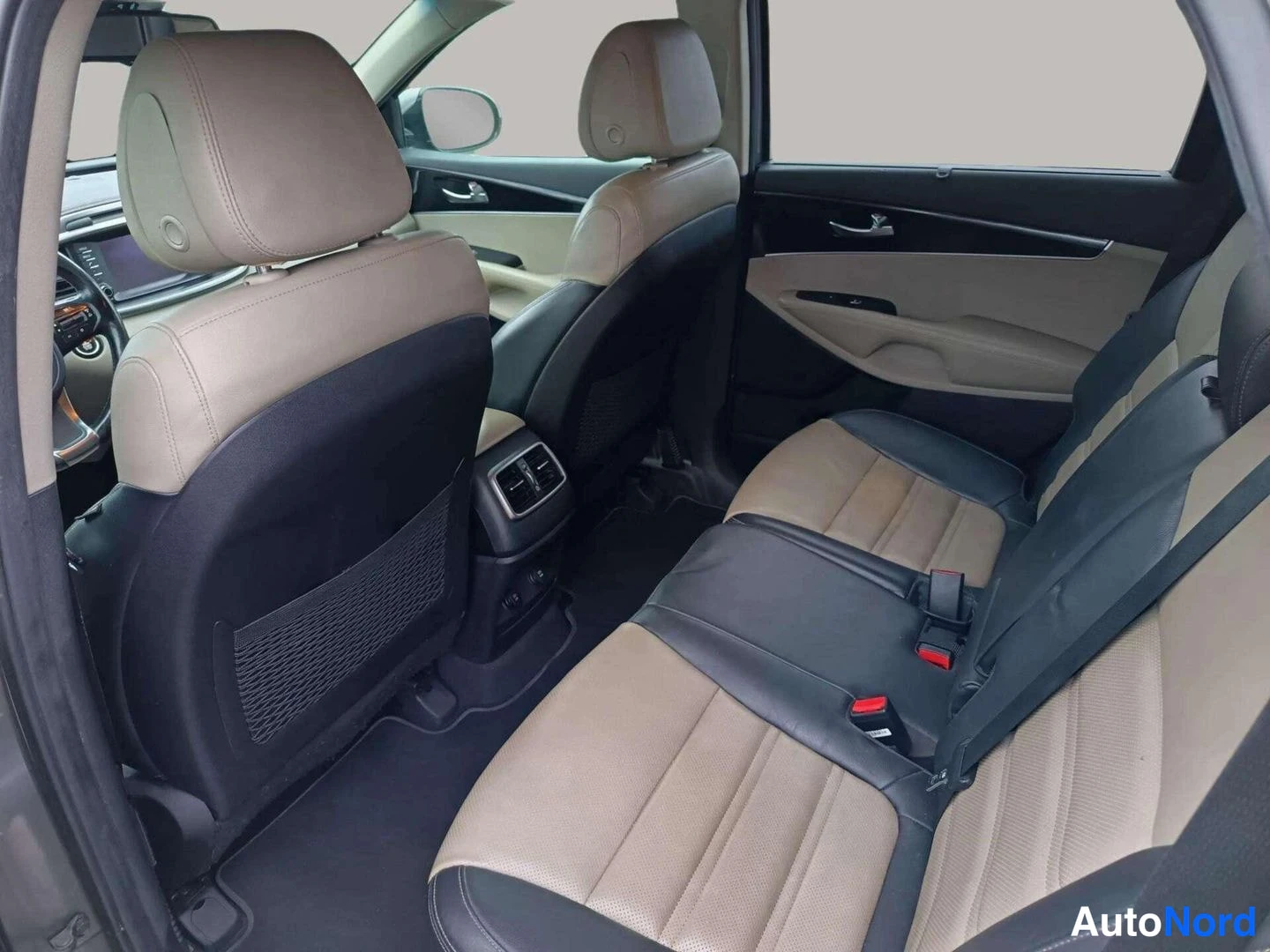 Takaistuimet: Rear passenger compartment displaying beige leather seats with black side bolsters, rear air vents on the back of the front seat, and headrests