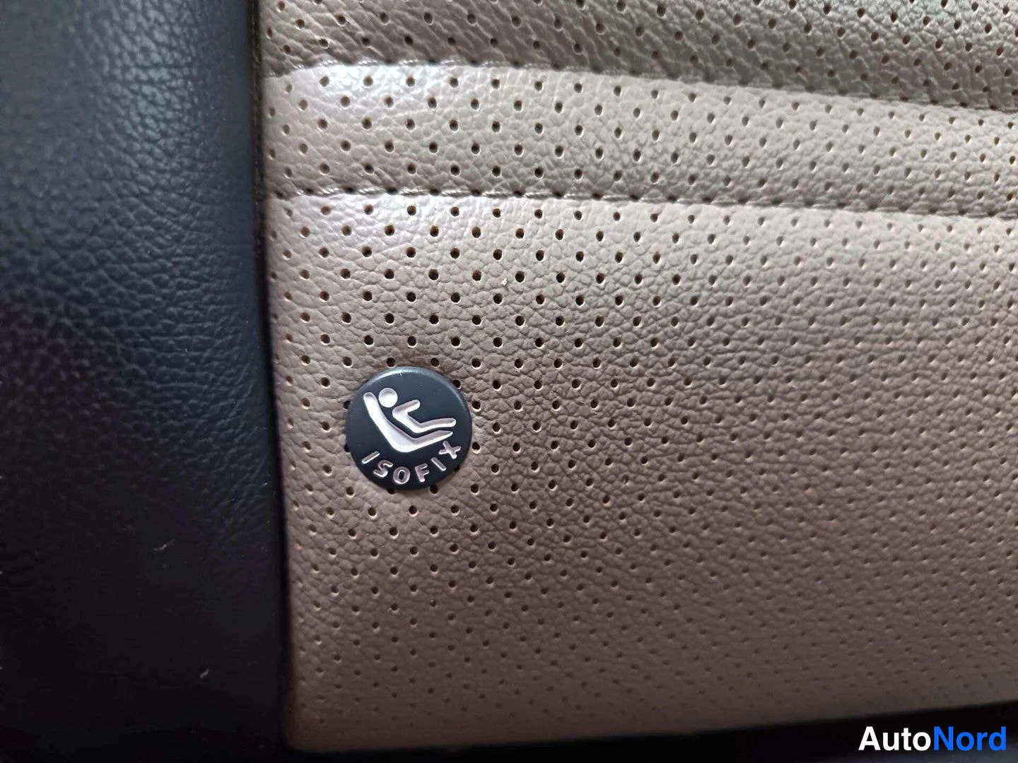 Muu: ISOFIX-merkki ruskeassa uritetussa nahkapenkin selustassa.