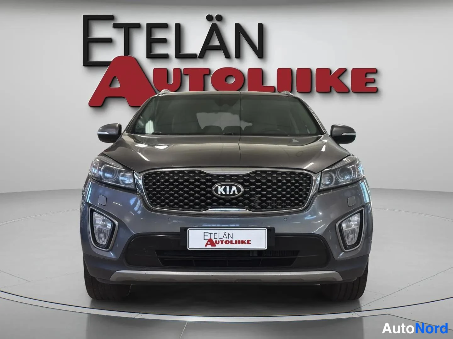 Edestä: Kia Sorenton etunäkymä, harmaa kori, KIA-merkki säleikössä ja Etelän Autoliiken valkoinen rekisterikilpimainen kyltti etupuskurissa.