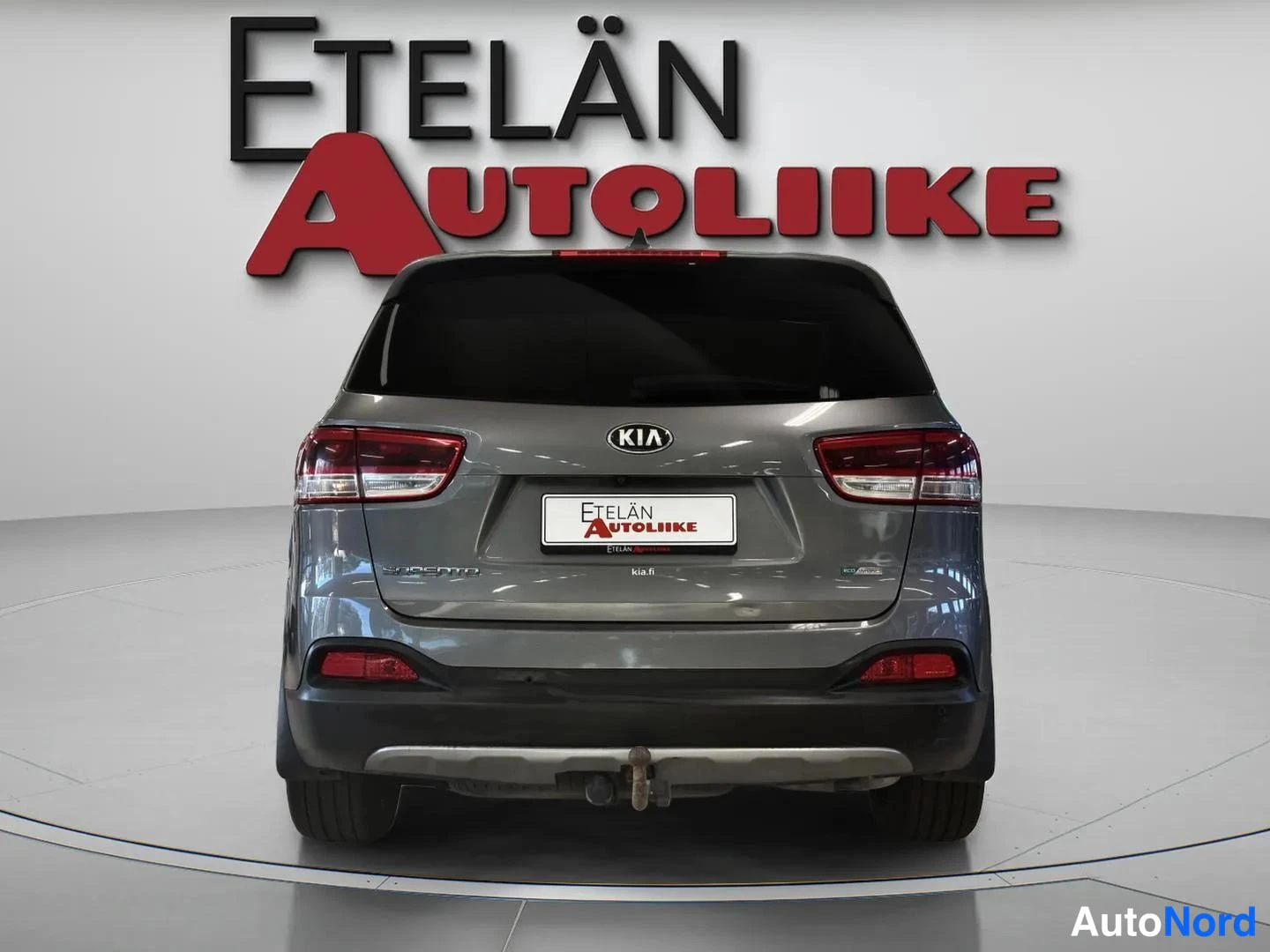 Takaa: Kia Sorento -farmarin takaosa, harmaa, takavalot ja Etelän Autoliike-kyltti rekisteritelineessä.