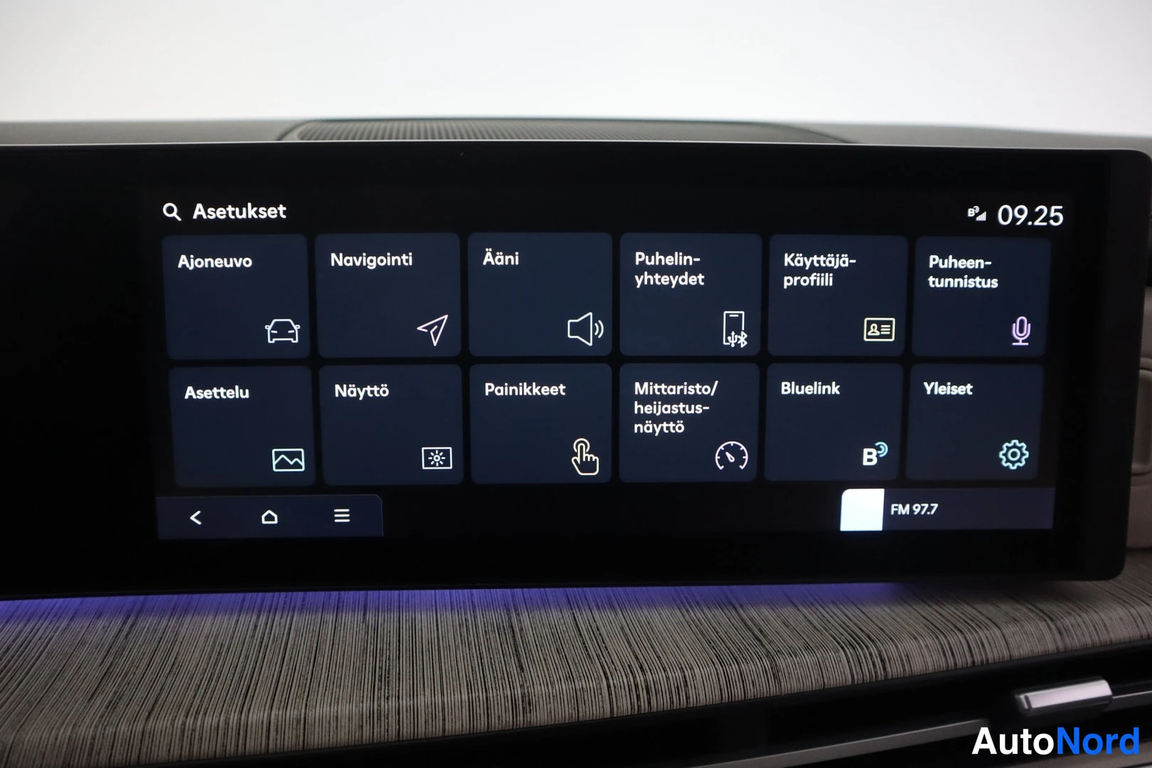 Yksityiskohta: Auton infotainment-näytön Asetukset-valikko, jossa ruudut Ajoneuvo, Navigointi, Ääni, Puhelin-yhteydet, Käyttäjä-profiili, Puheentunnistus, Asettelu, Näyttö, Pa